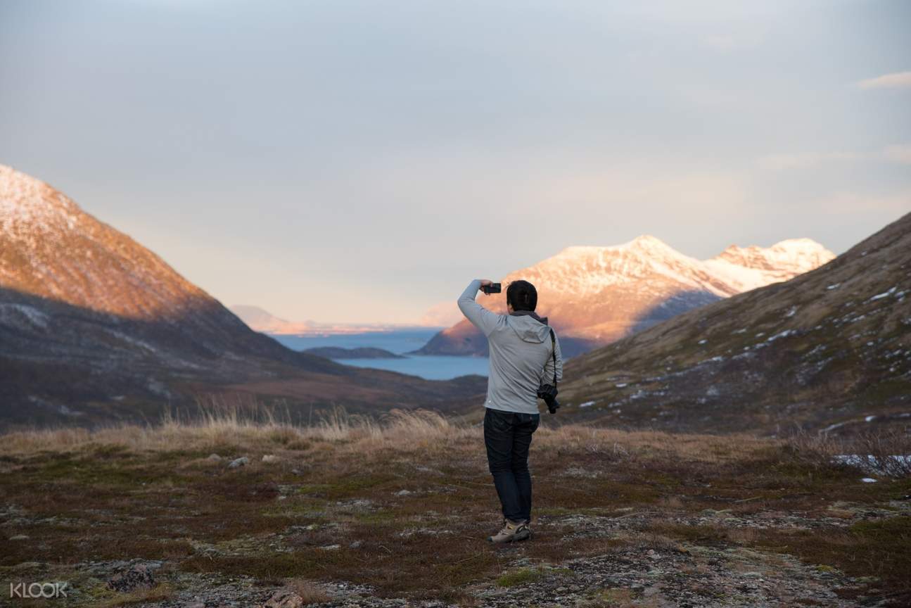 woman taking photos of the arctic mountains