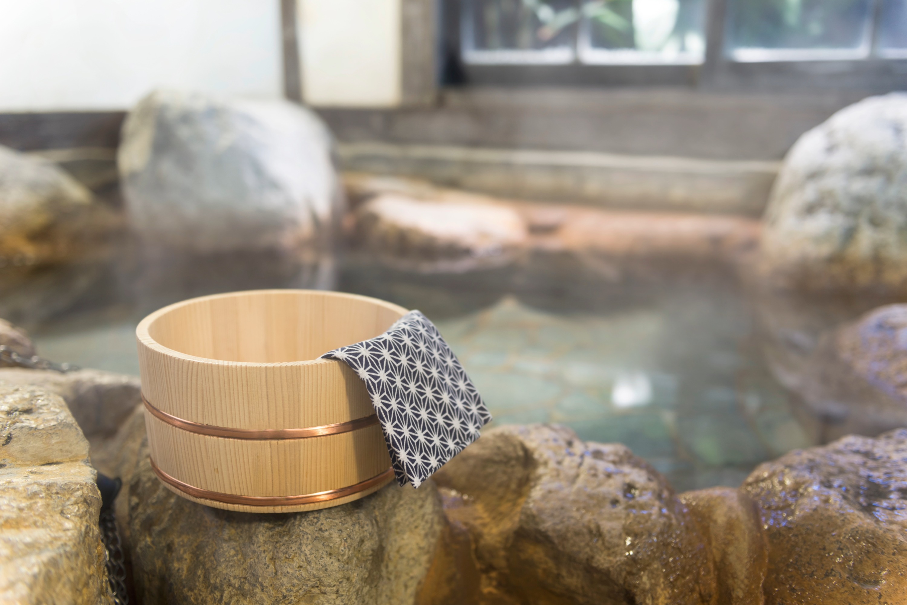 A tranquil and inviting Japanese open-air hot spring, or ""rotenburo,"" set in a serene winter landscape.