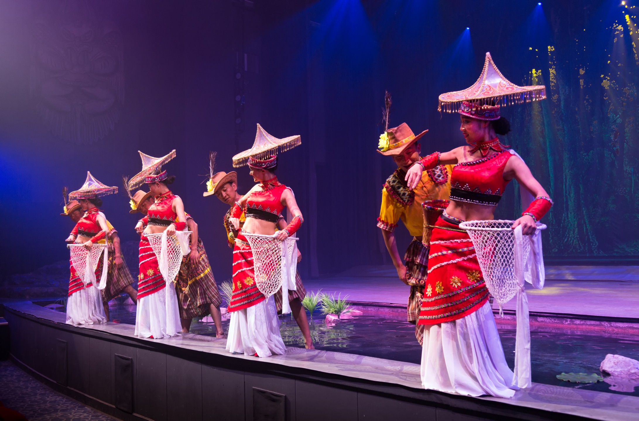 身著紅金流蘇裙、頭戴斗笠的舞者呈一字排開，動作整齊劃一