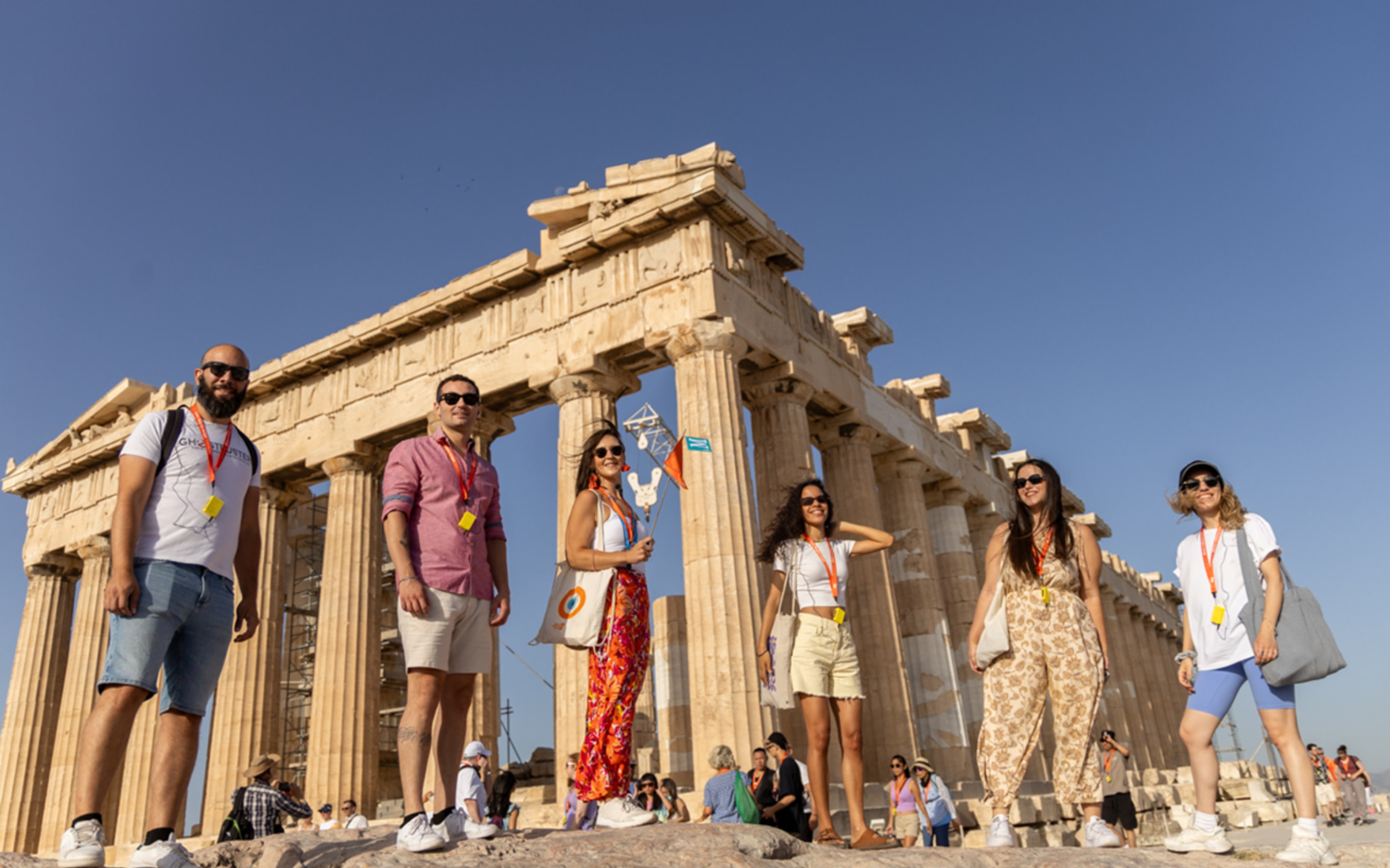 陽光下，笑容滿面的旅客們在宏偉的雅典衛城遺址前驕傲地合影，捕捉永恆的回憶。