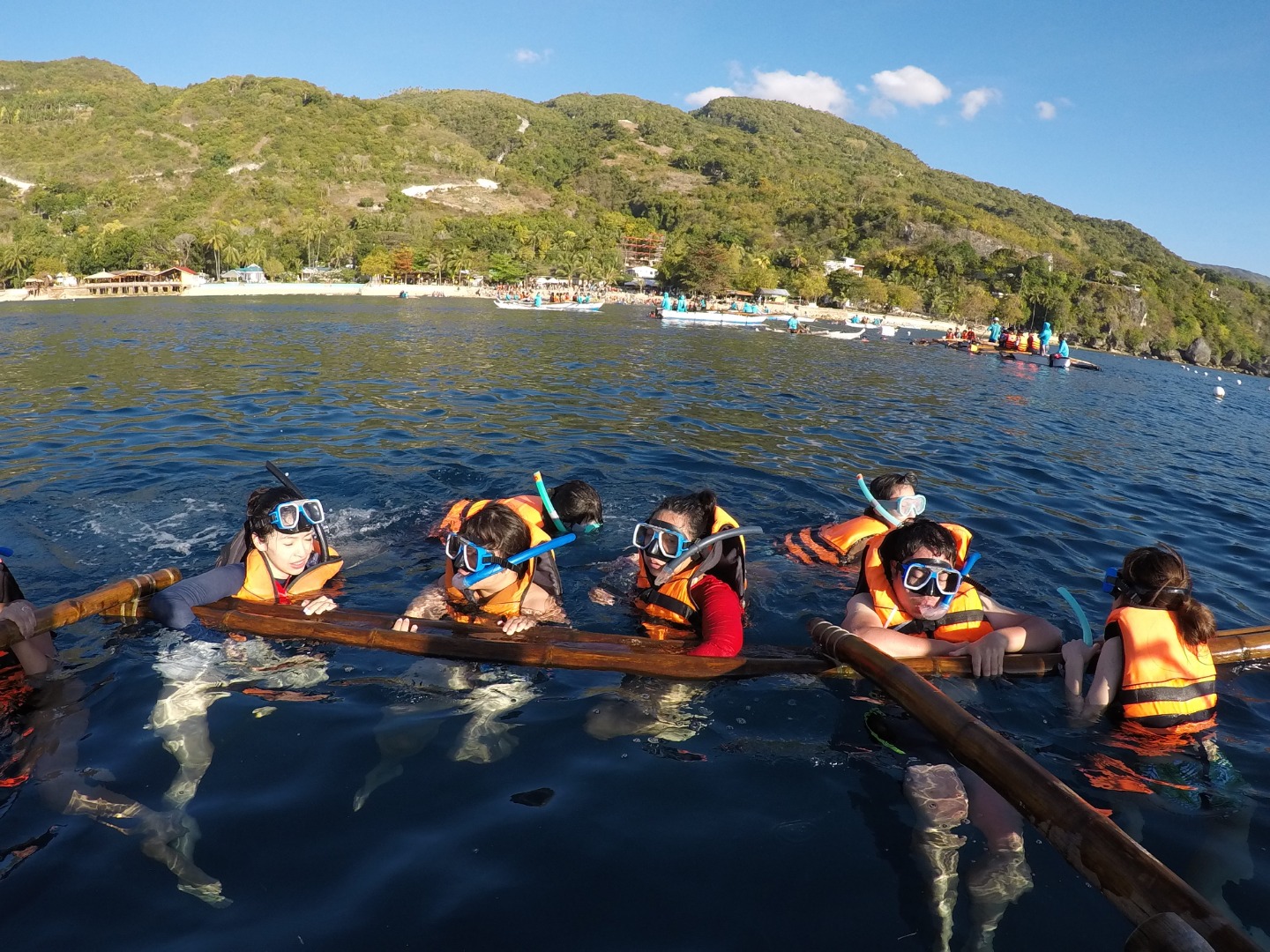 group of people with snorkeling gear floating on the surface of the water wearing life vests