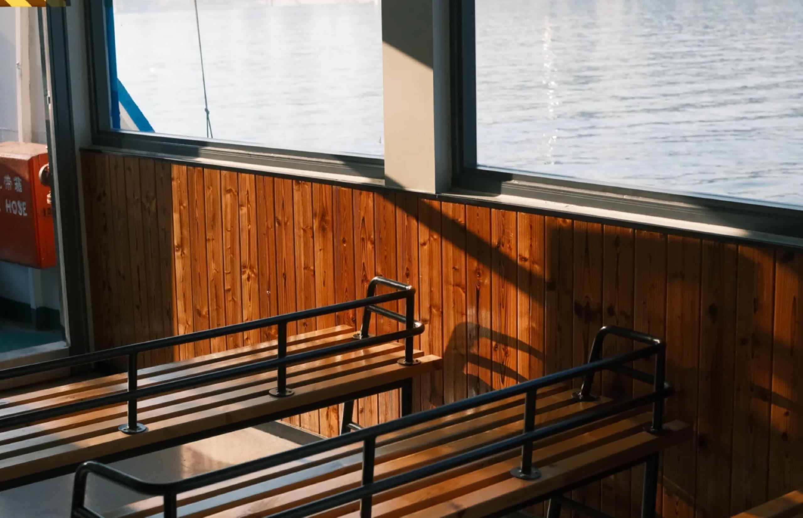 一層船艙裡，深棕色木質座椅整齊排列，椅面磨得發亮，彷彿藏著近 90 年的跨江故事