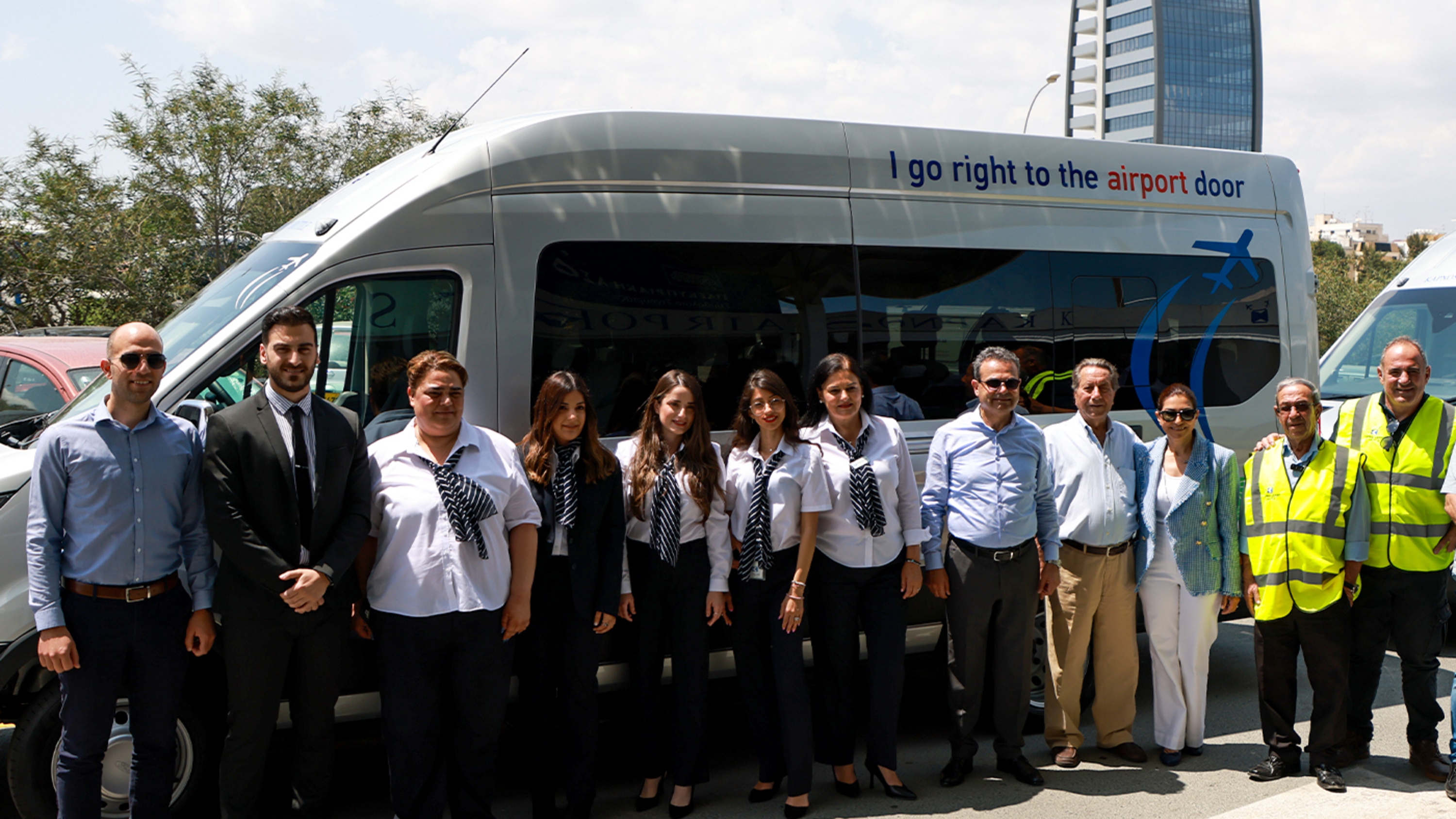 Friendly staff members posing and smiling in front of the shuttle bus vehicle