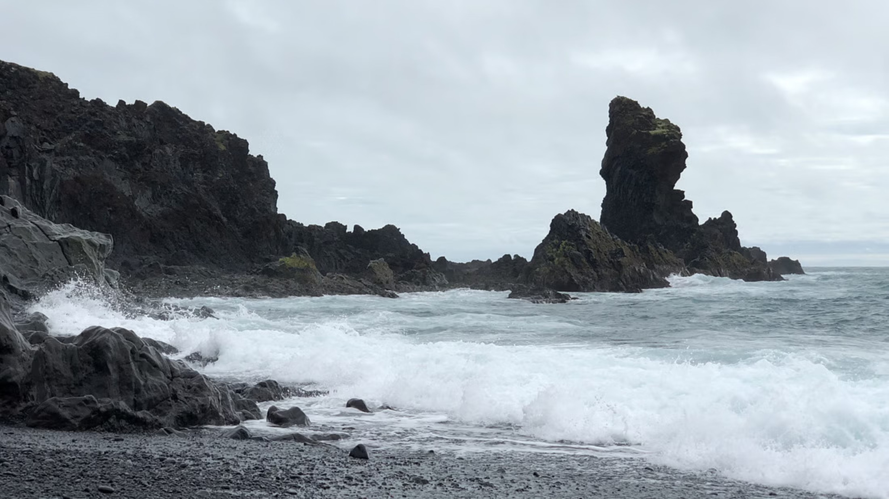 Djupalonssandur beach features black volcanic sand, dramatic rock formations, and historic shipwreck remains