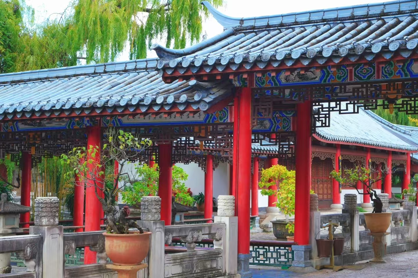 木府中式迴廊景緻雅緻，硃紅立柱整齊排列，青瓦廊頂的藍綠彩繪細膩