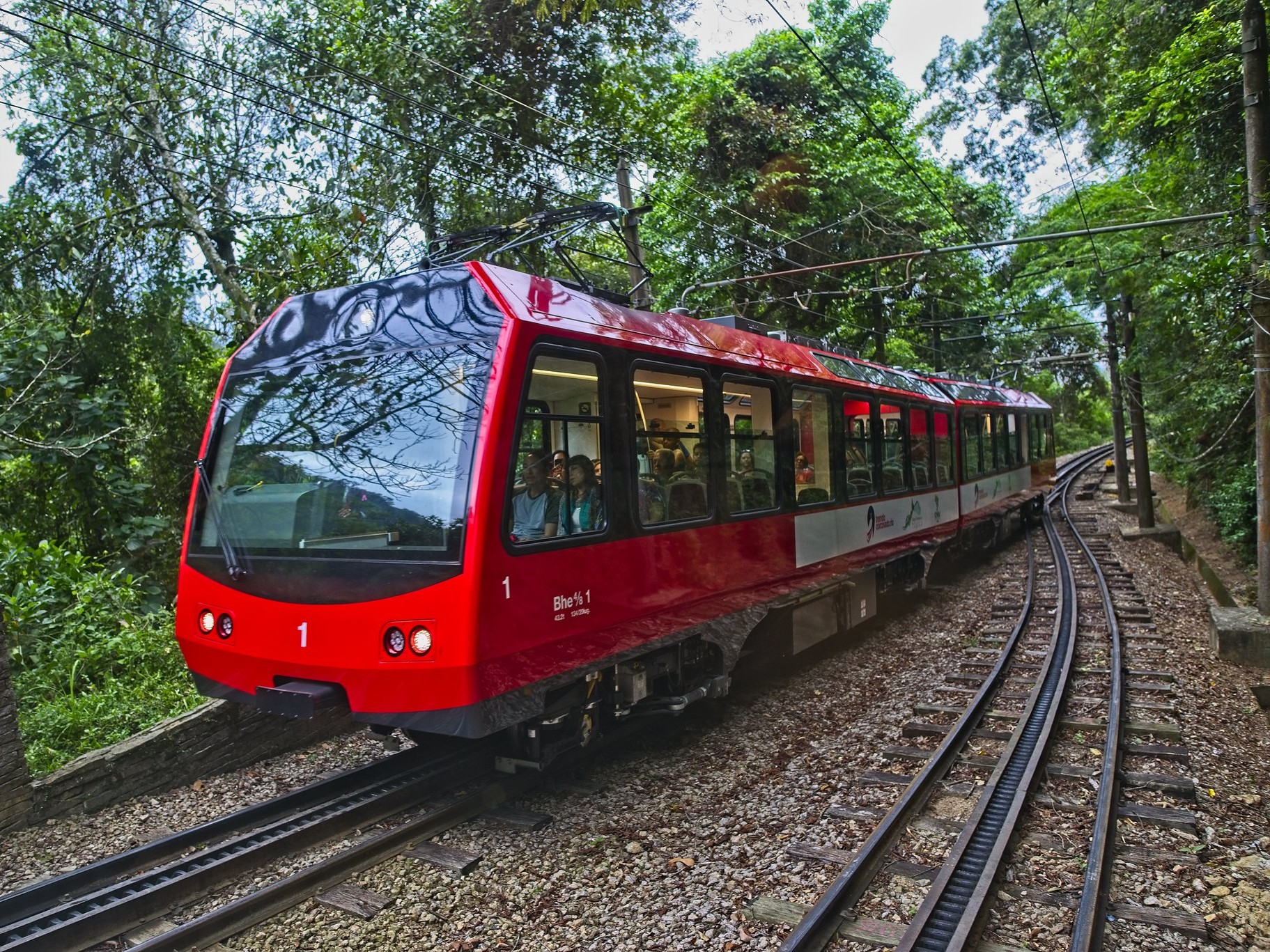 Scenic train winding through Tijuca Forest, heading toward Christ the Redeemer's towering statue