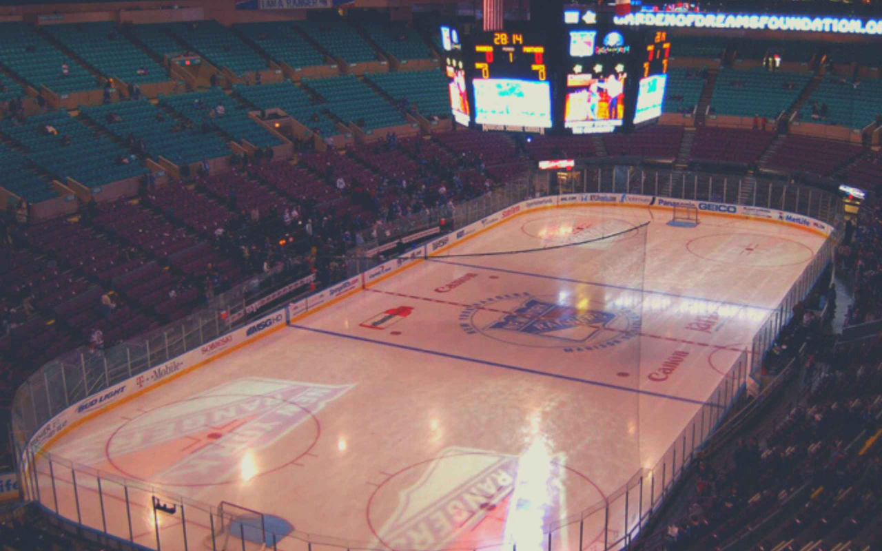 廣角視角下的溜冰場，遊騎兵隊球員正朝著冰球衝刺。