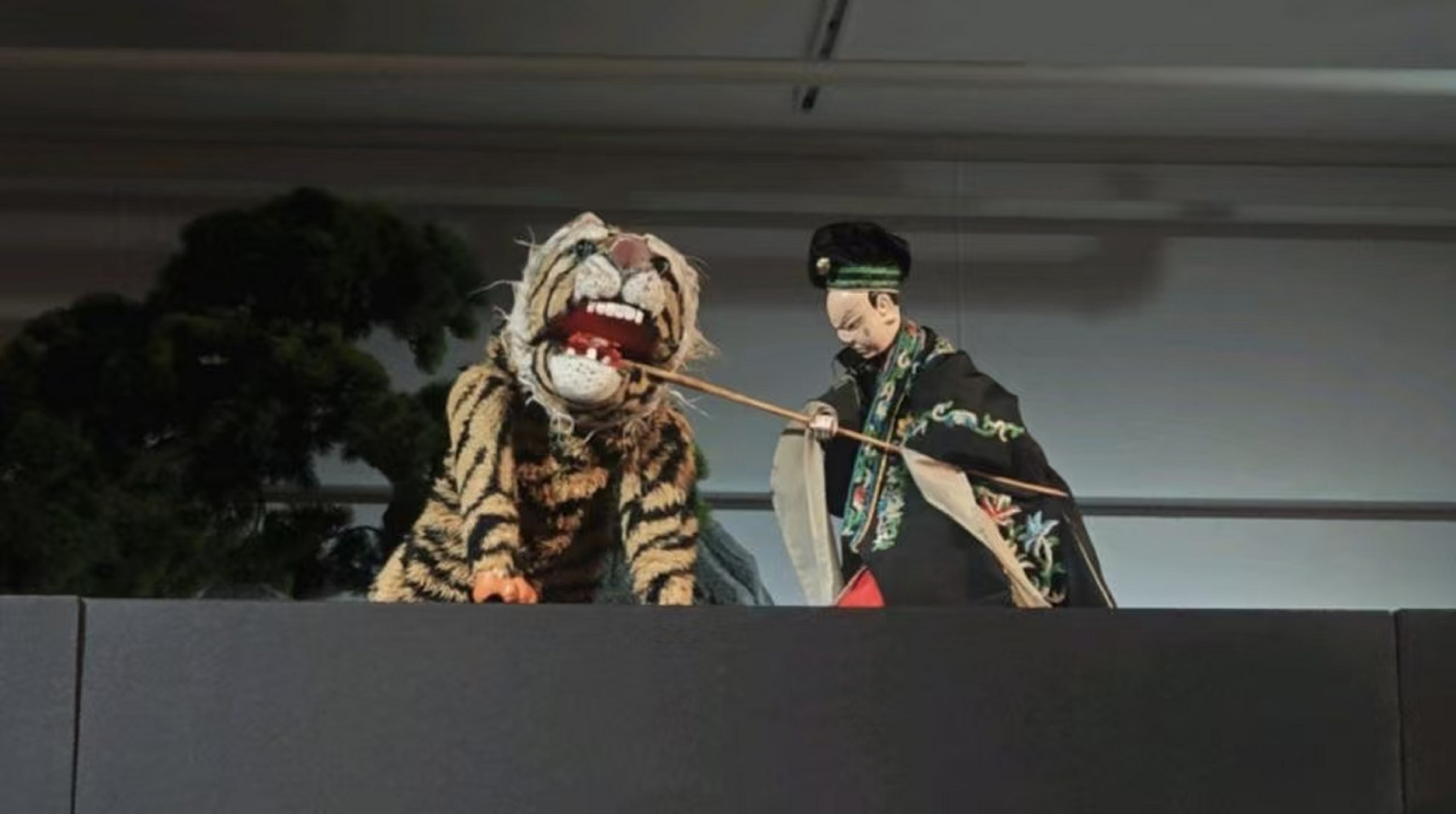 衣袍上的彩繡隨著動作輕晃，把《武松打虎》裡的驚險，攥在了這寸許的木偶戲臺上