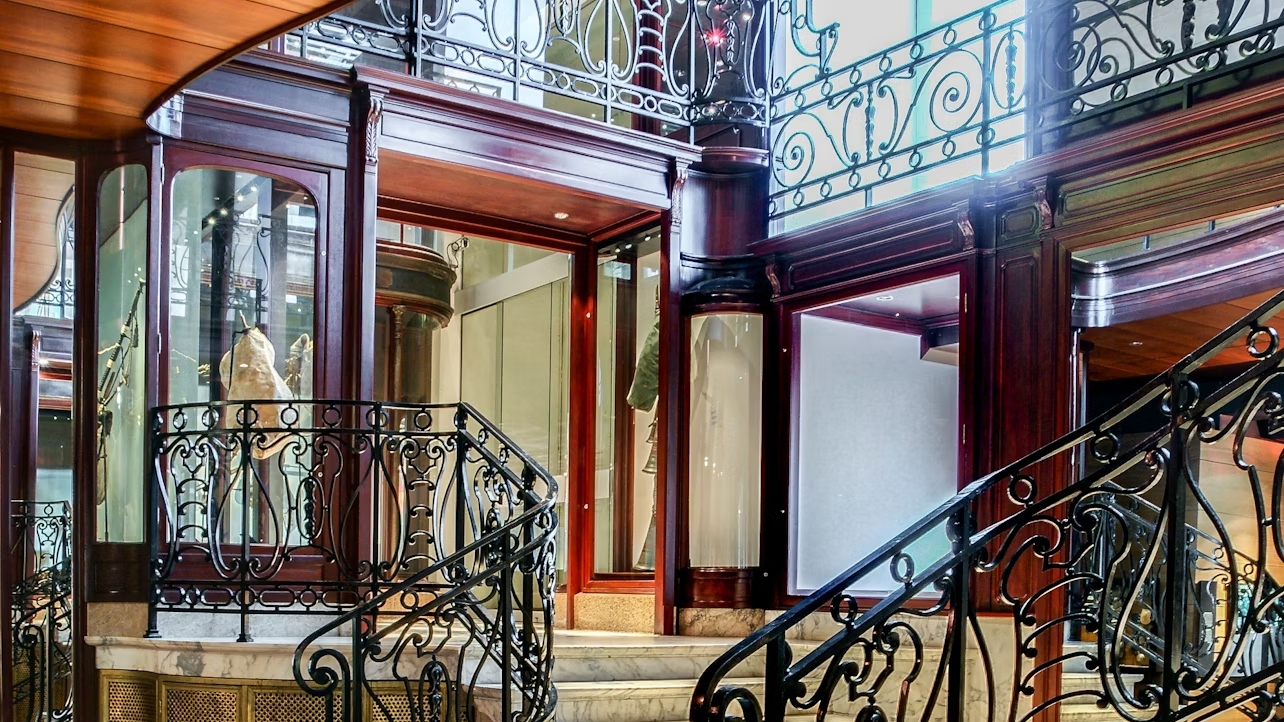 Expansive glass windows reflect the cityscape, blending Art Nouveau design with modern elegance