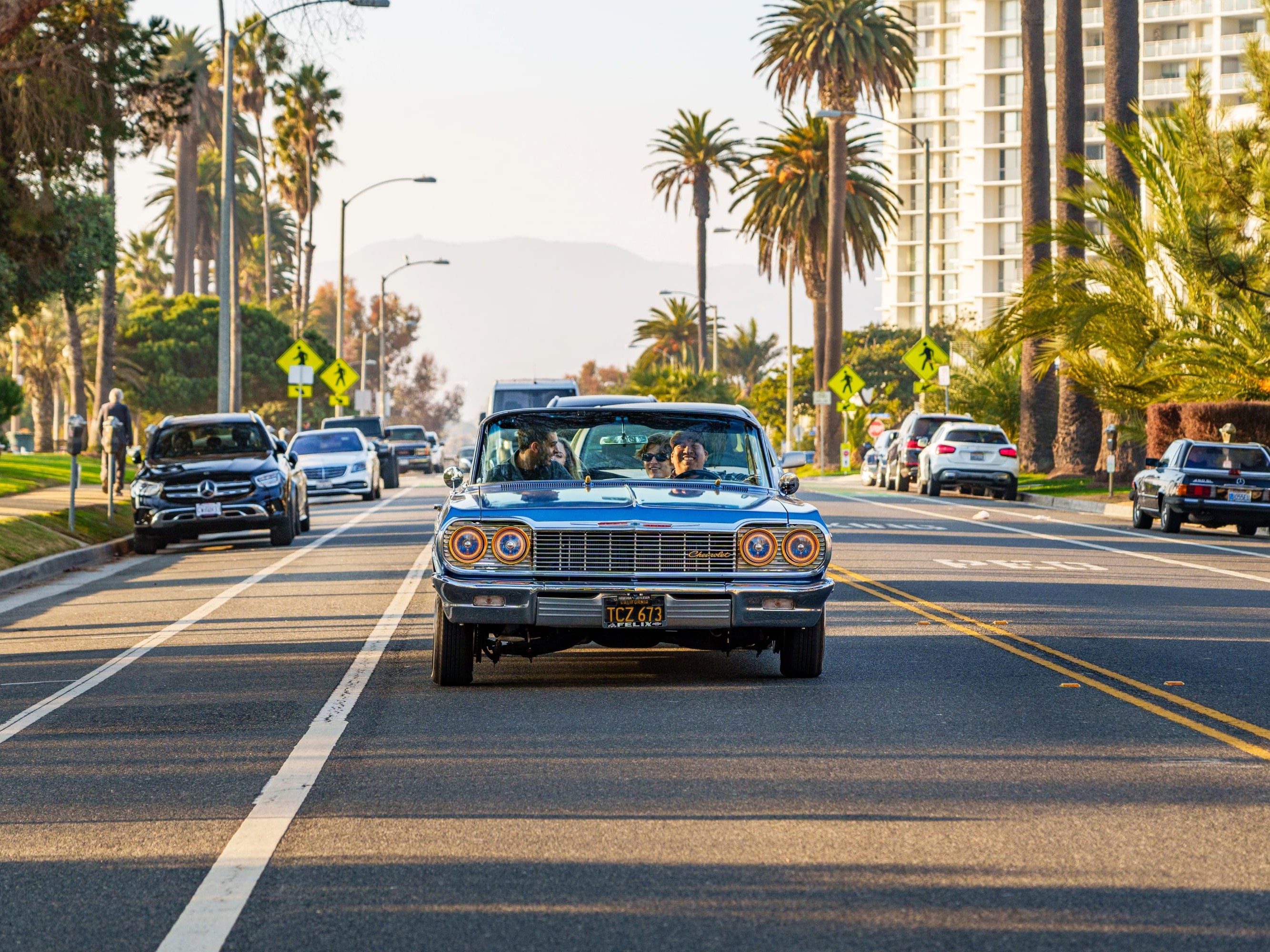 A classic ‘64 lowrider cruising down LA streets, reflecting vibrant city lights