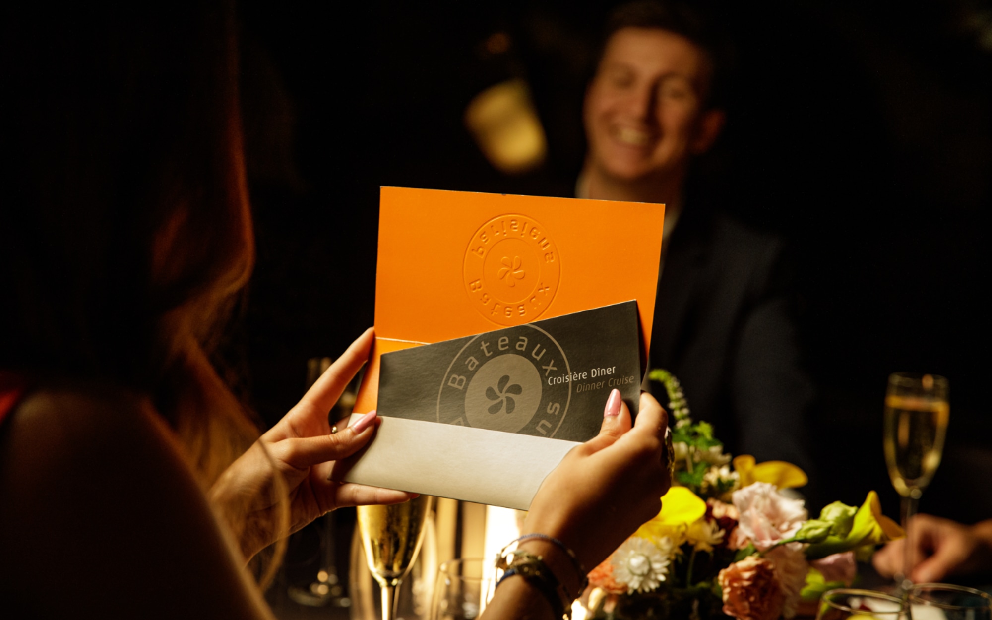 賓客們在巴黎塞納河上享受優雅的夜間遊船之旅,一邊品嚐燭光晚餐,一邊欣賞城市璀璨的燈光地標,沉浸在精緻的氛圍中,並仔細研究菜單。 賓客們在巴黎塞納河上享受優雅的夜間遊船之旅,一邊品嚐燭光晚餐,一邊欣賞城市璀璨的燈光地標,沉浸在精緻的氛圍中,並仔細研究菜單。