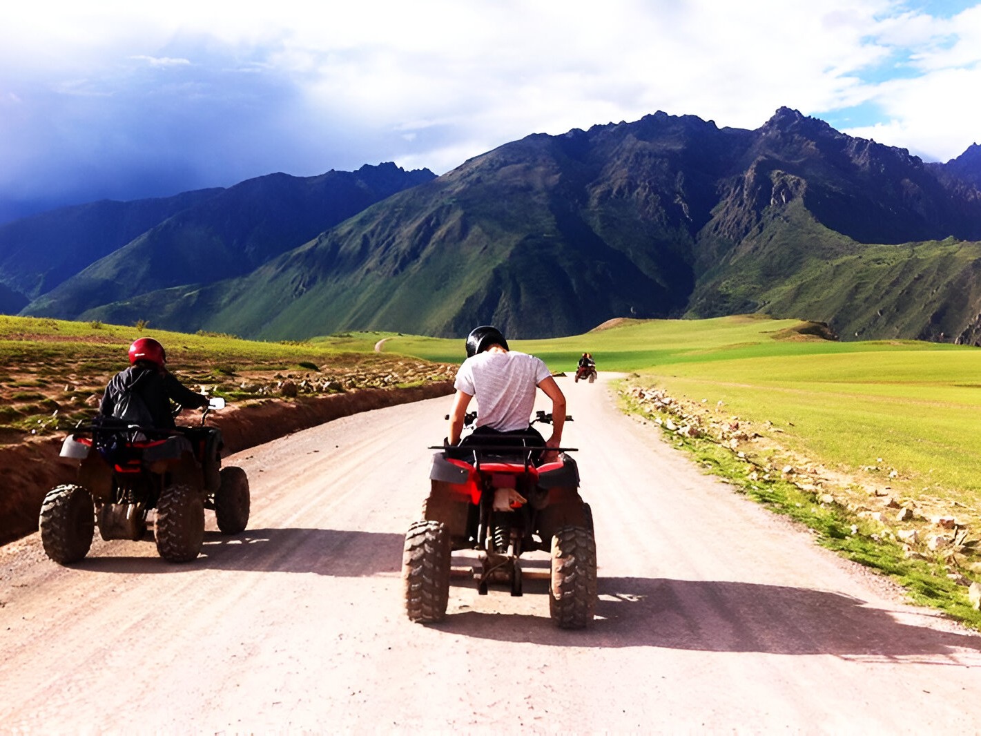 ATV convoy cruising past grazing alpacas in the lush countryside near Cusco