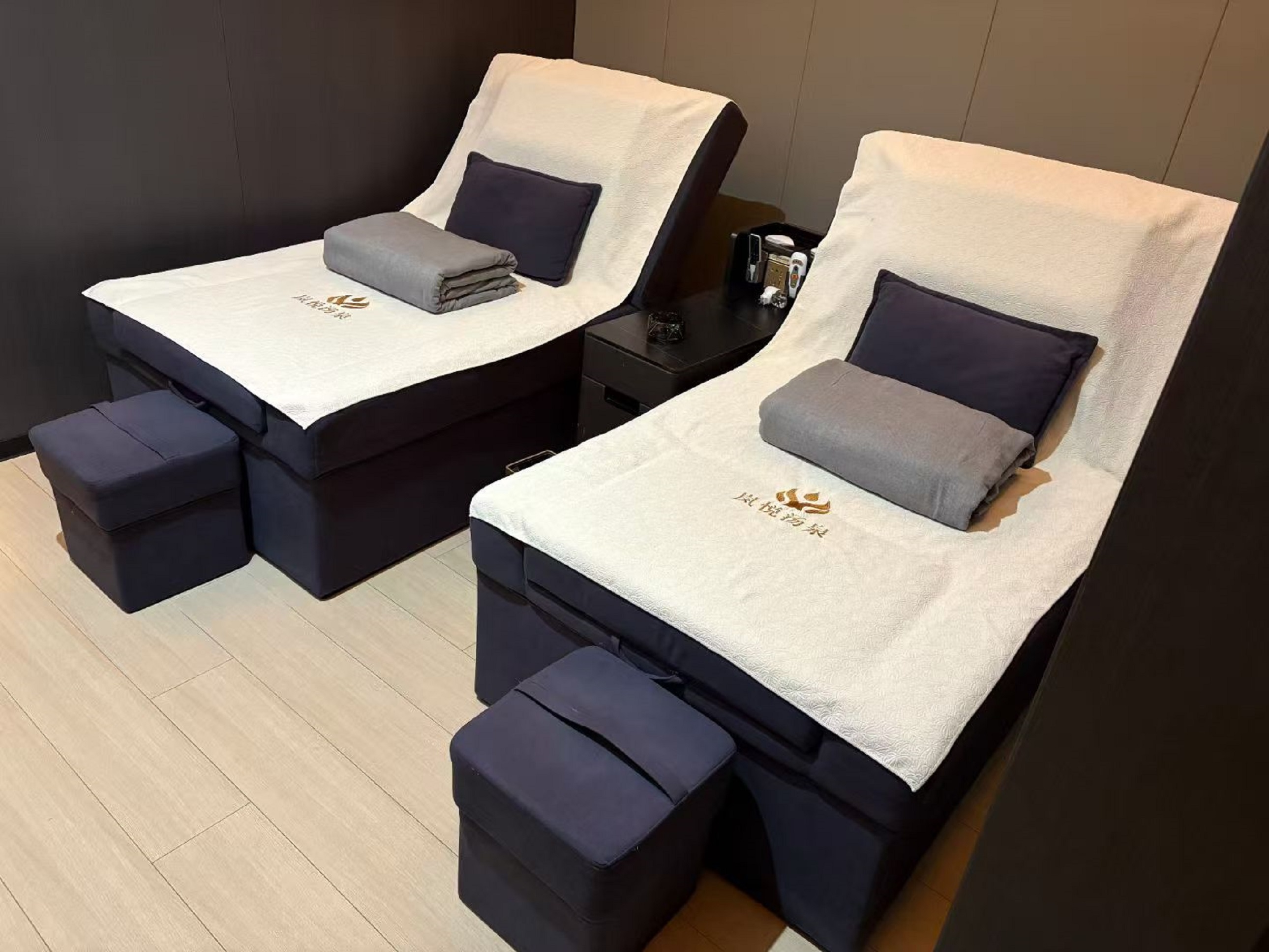 足療區擺放著兩張深藍色的足療床,床上鋪著白色的毛巾,配有灰色的抱枕和毯子,旁邊的小桌上還放著一些物品,這裡靜謐舒適,放鬆身心的好地方 足療區擺放著兩張深藍色的足療床,床上鋪著白色的毛巾,配有灰色的抱枕和毯子,旁邊的小桌上還放著一些物品,這裡靜謐舒適,放鬆身心的好地方