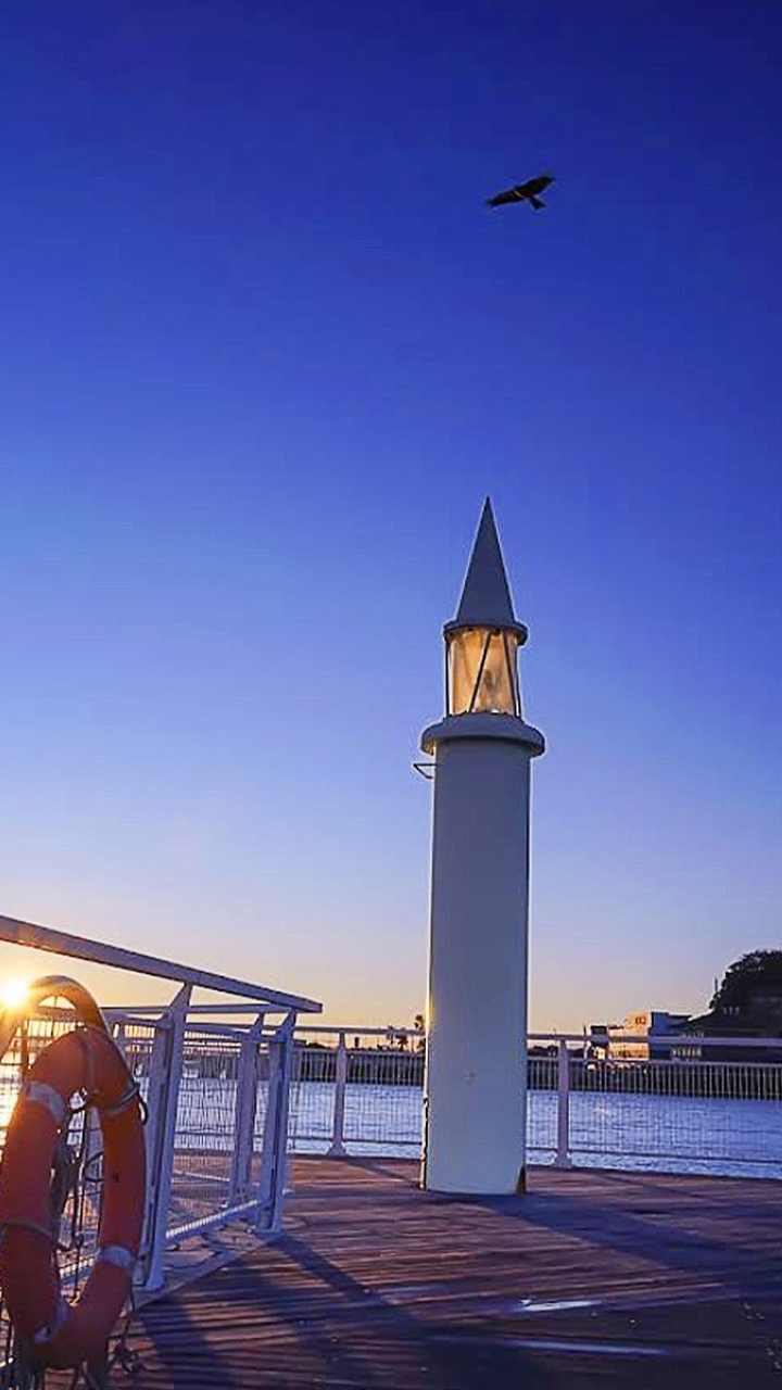 白色燈臺靜立海岸,蔚藍海面波光粼粼,遠望湘南海景開闊清朗,海風輕拂,盡顯漁港寧靜悠然氛圍 白色燈臺靜立海岸,蔚藍海面波光粼粼,遠望湘南海景開闊清朗,海風輕拂,盡顯漁港寧靜悠然氛圍