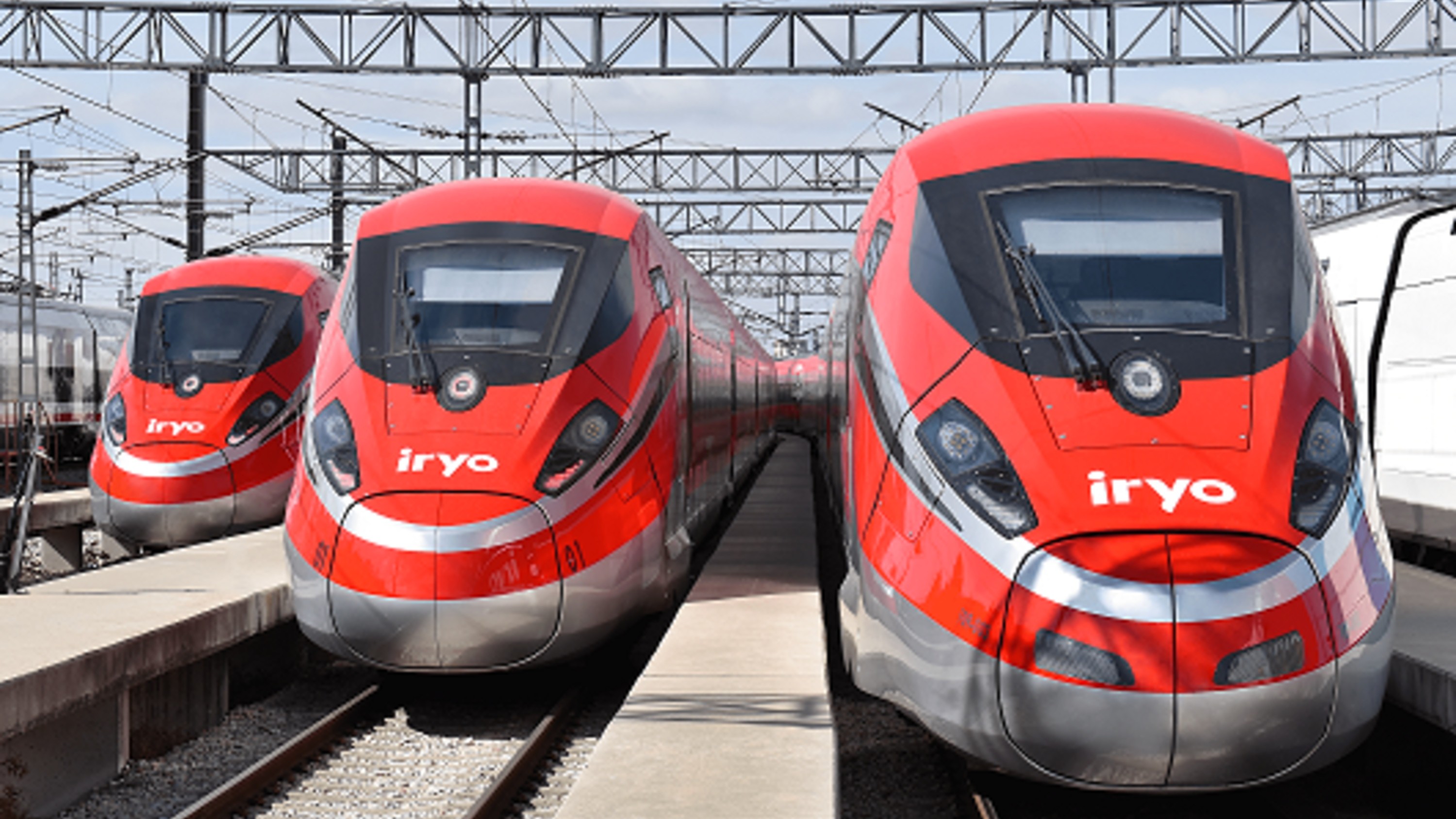 A modern train stationed at Barcelona Sants, ready for departure under clear blue skies