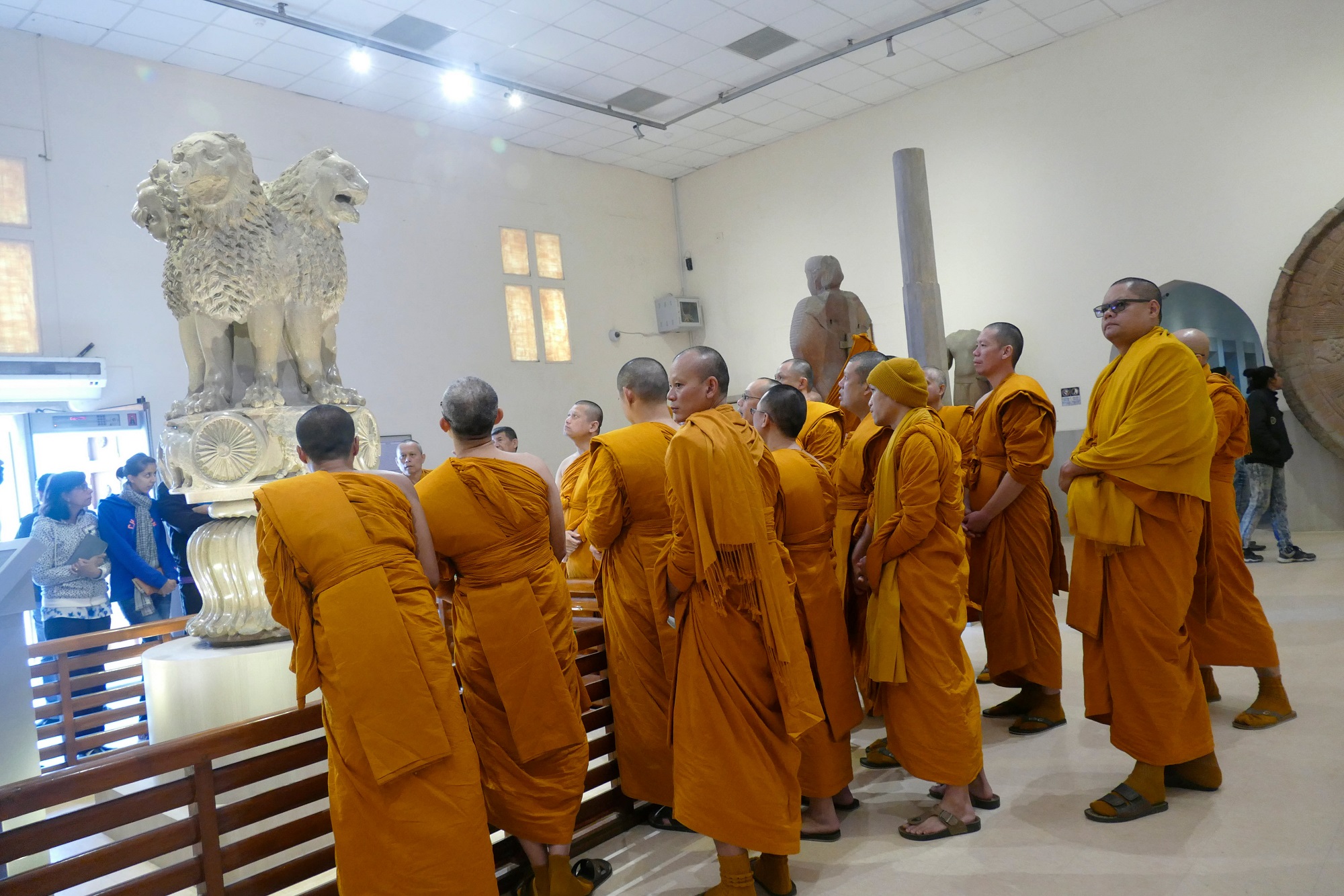 Buddhist monks examine sculptures in the museum at Sarnath with our Guide near Varanasi city.