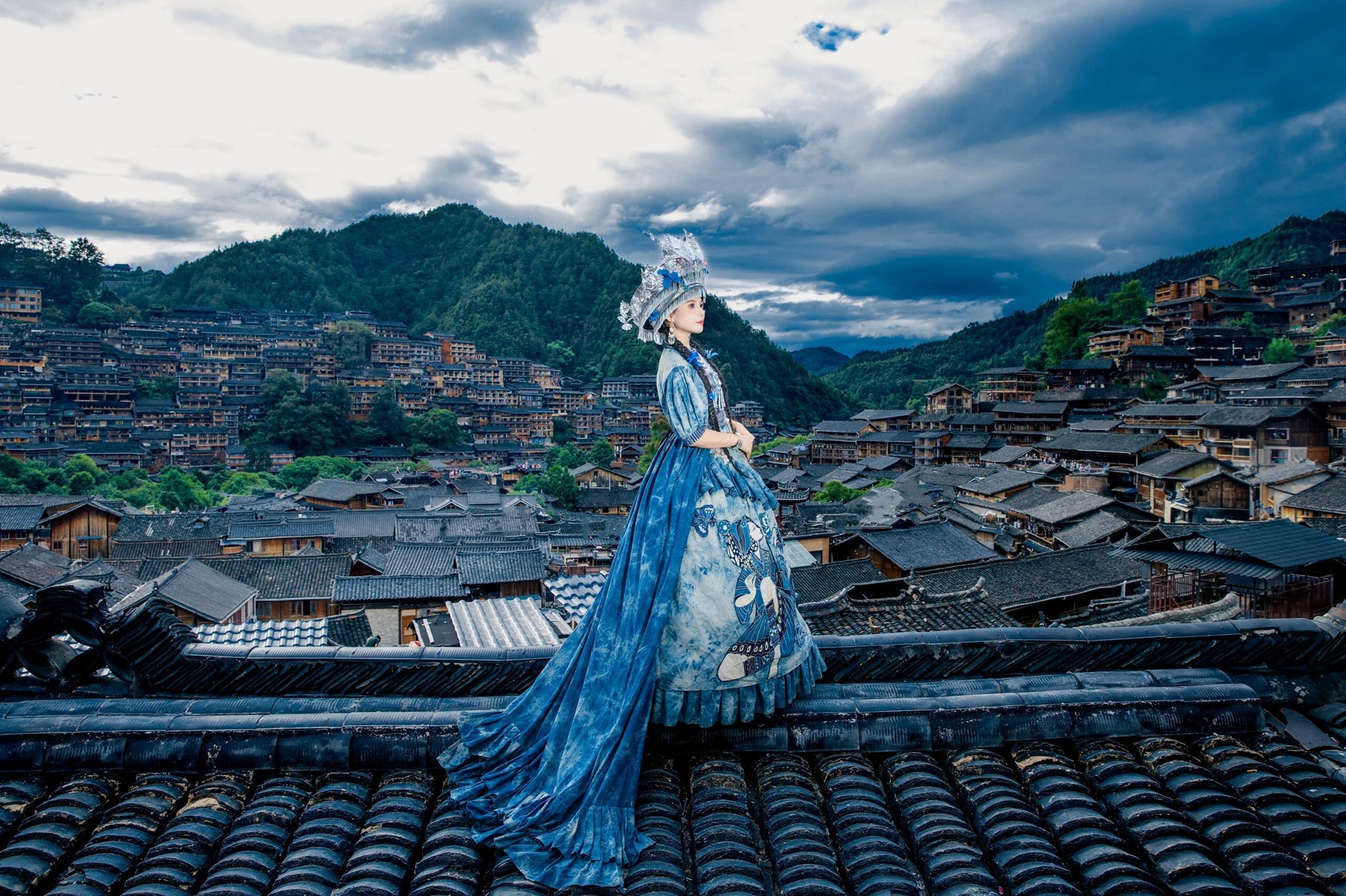 著一襲苗衣立於屋頂,背後是西江千戶苗寨的層疊屋宇。時光在此刻凝駐,繪就一幅古韻風華圖 著一襲苗衣立於屋頂,背後是西江千戶苗寨的層疊屋宇。時光在此刻凝駐,繪就一幅古韻風華圖