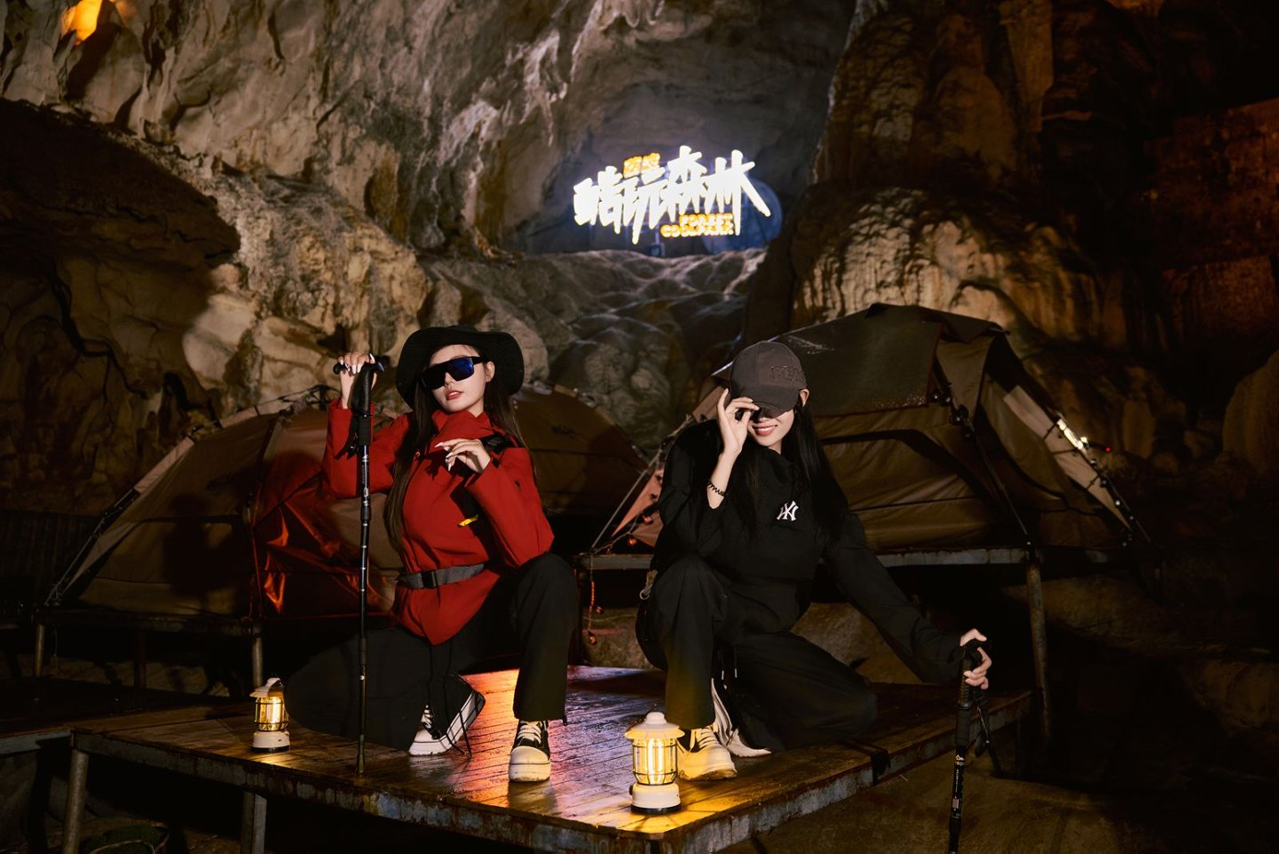 溶洞營地的木臺上,兩位潮酷女孩在 “酷玩森林” 燈牌前打卡,紅黑穿搭與帳篷、煤油燈相映,暖光營造出野奢出片的氛圍 溶洞營地的木臺上,兩位潮酷女孩在 “酷玩森林” 燈牌前打卡,紅黑穿搭與帳篷、煤油燈相映,暖光營造出野奢出片的氛圍