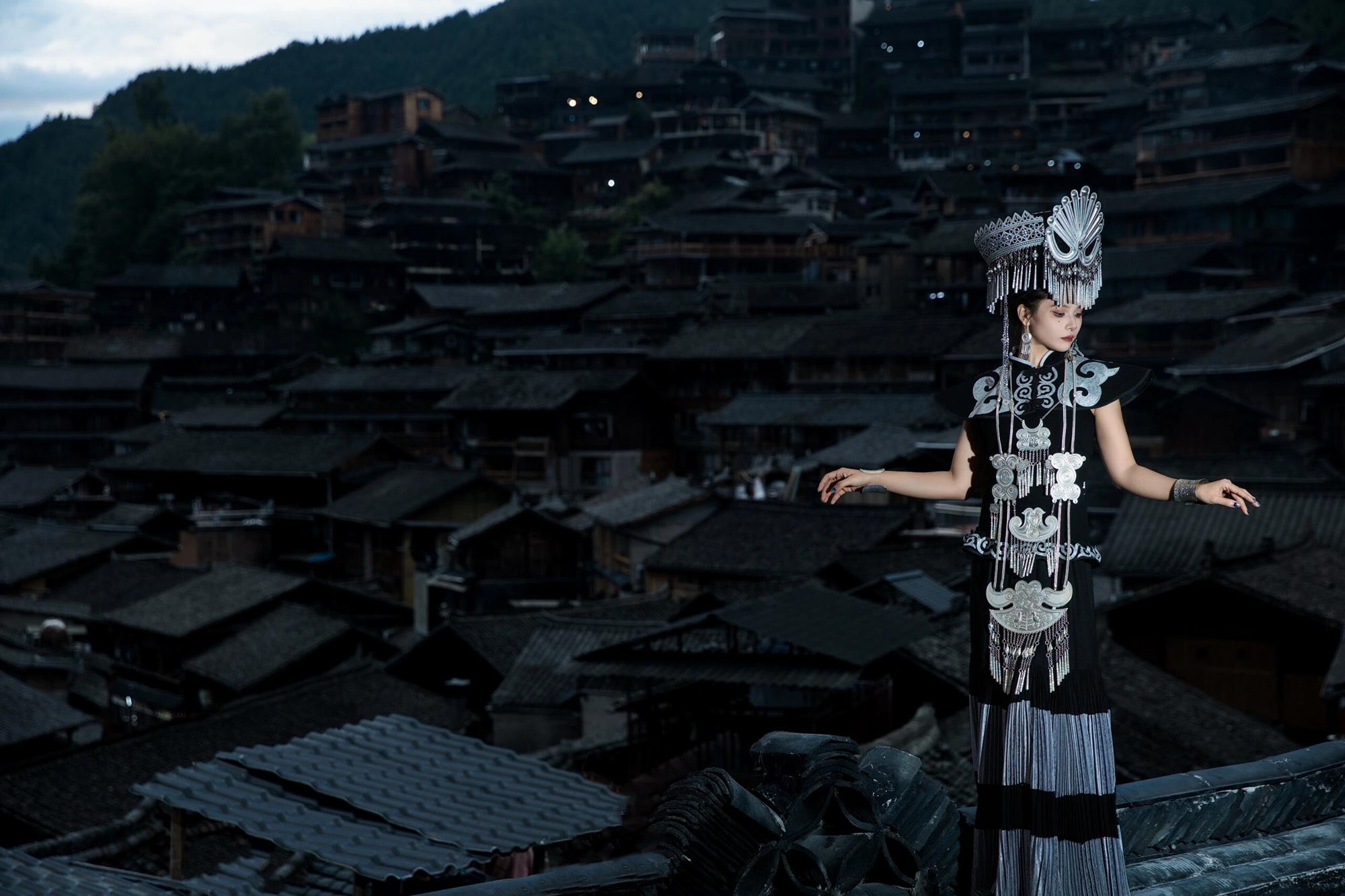 夜幕垂落,苗寨隱於暗影。身著銀飾盛裝的女子優雅而立,繪就西江千戶苗寨的綺麗風情 夜幕垂落,苗寨隱於暗影。身著銀飾盛裝的女子優雅而立,繪就西江千戶苗寨的綺麗風情