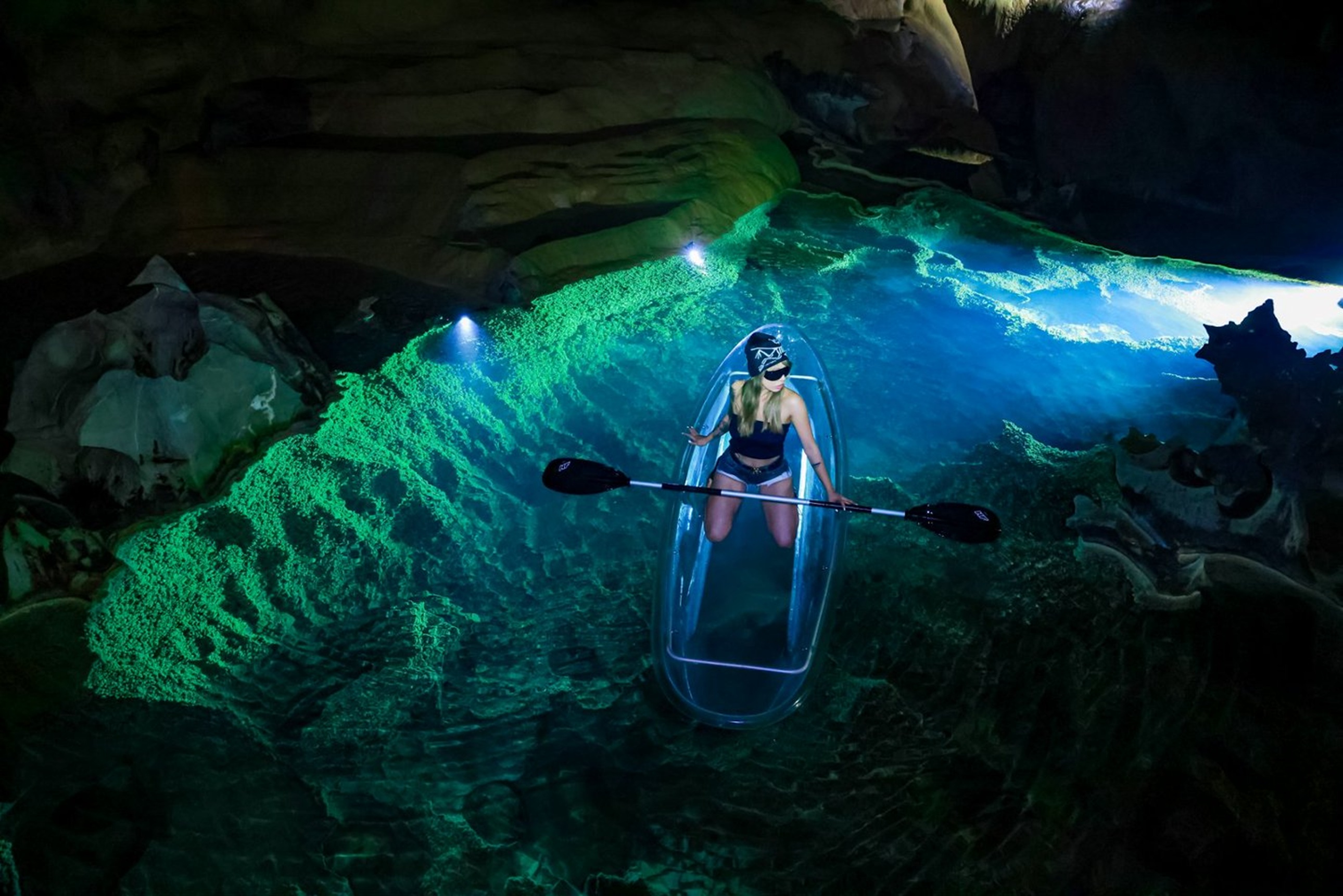 女孩乘透明皮划艇遊弋在溶洞暗河,綠藍燈光在水面流轉,巖壁紋理清晰可見,彷彿穿行於地心秘境的奇幻星河 女孩乘透明皮划艇遊弋在溶洞暗河,綠藍燈光在水面流轉,巖壁紋理清晰可見,彷彿穿行於地心秘境的奇幻星河