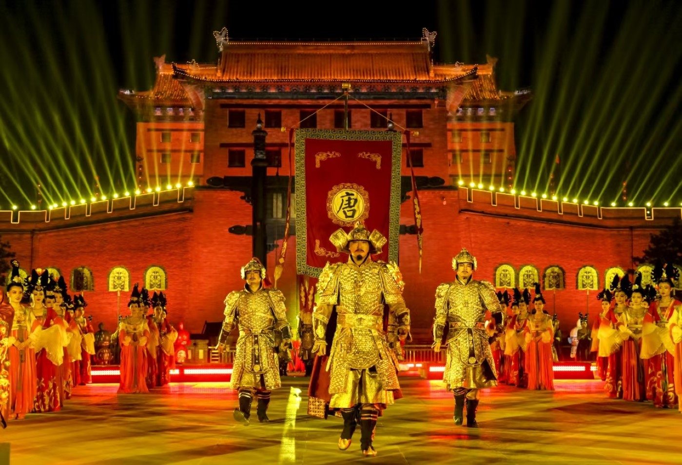 幾位身著金光閃閃鎧甲的武士邁步向前，氣場強大，他們身後是眾多穿著華麗唐裝的演員整齊列隊