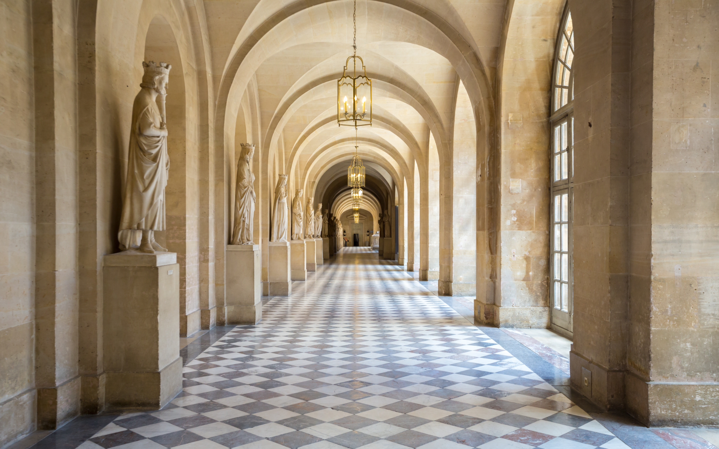 Marble statues standing gracefully along the hallways of the Palace of Versailles