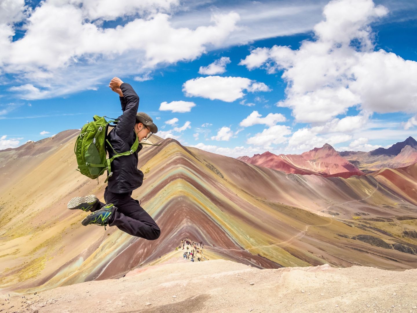 Jump high and pose proudly with Rainbow Mountain’s colorful backdrop behind you