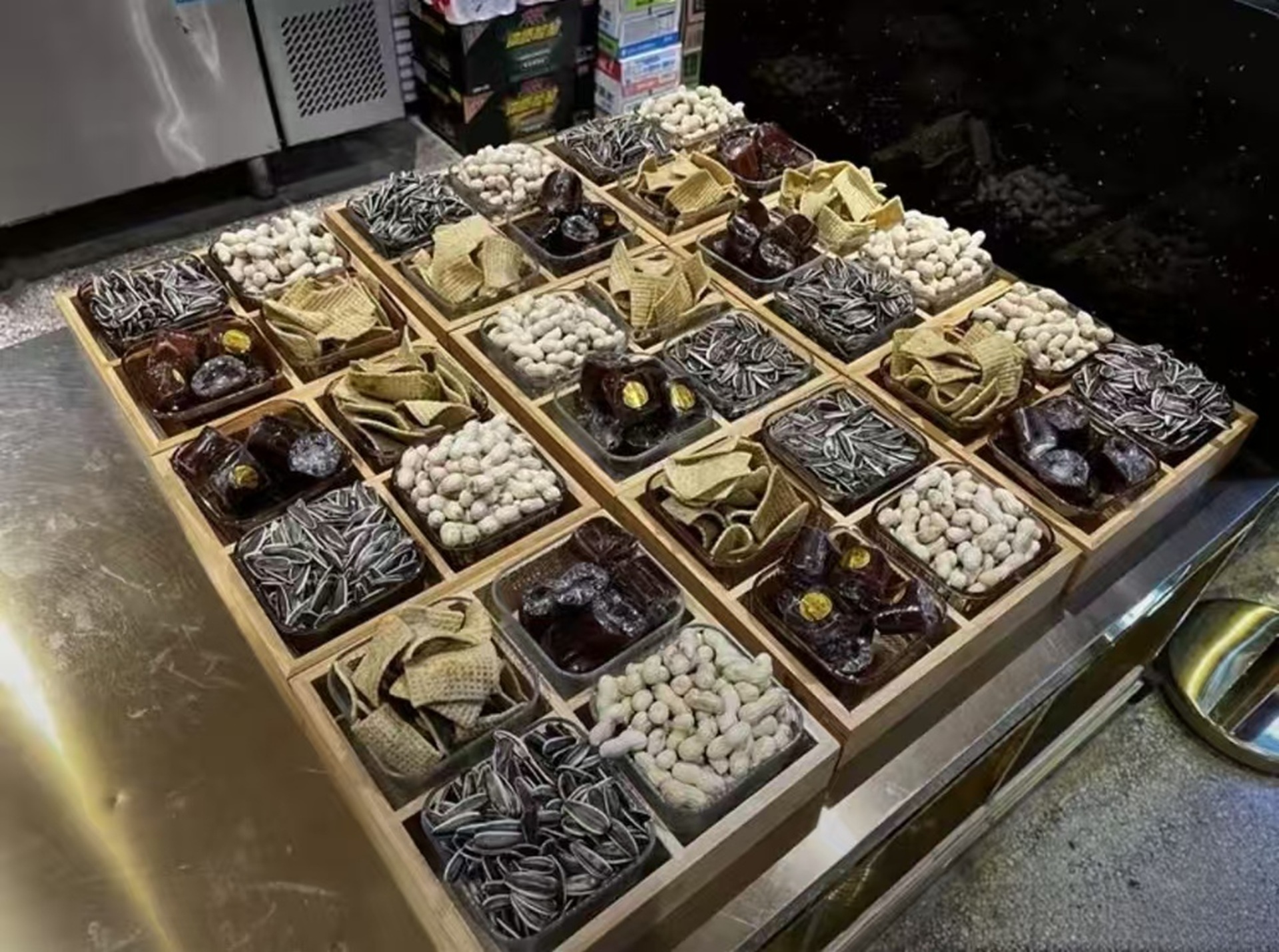 檯面擺滿分格木盒，內裝瓜子、花生、糕點等零食，種類豐富，是常見的小吃售賣陳列