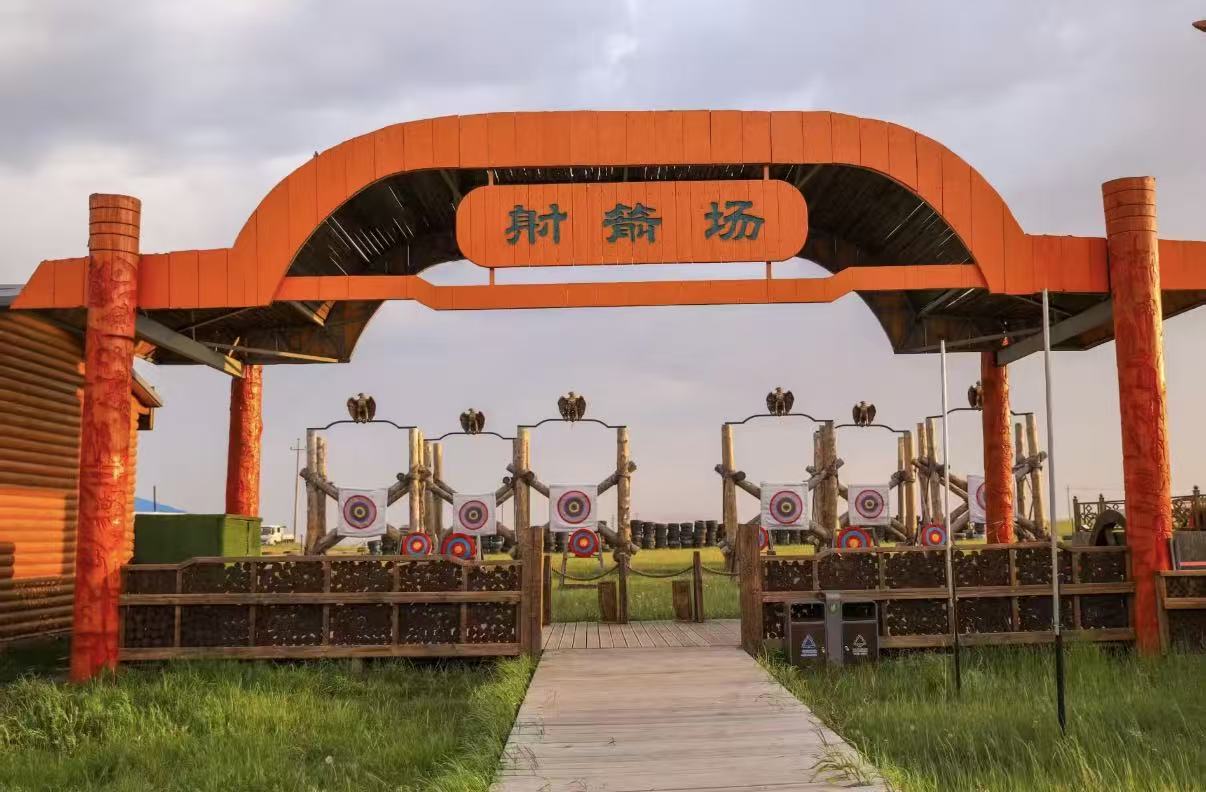 草原特色射箭場拱門古樸橙紅,木牌書寫射箭場三字。原木搭建靶道整齊排布箭靶,鷹鵰擺件點綴架上,木屋與青草地環繞場地,可體驗傳統蒙古射箭,感受草原特色休閒項目 草原特色射箭場拱門古樸橙紅,木牌書寫射箭場三字。原木搭建靶道整齊排布箭靶,鷹鵰擺件點綴架上,木屋與青草地環繞場地,可體驗傳統蒙古射箭,感受草原特色休閒項目