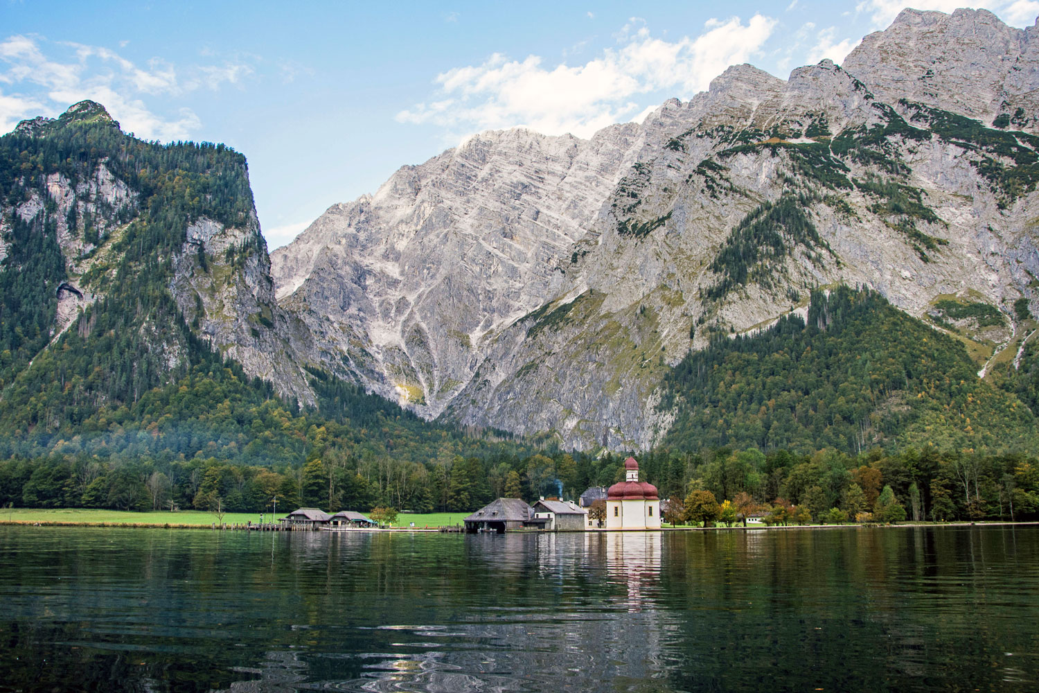 bavarian mountains towering over house and  lake 