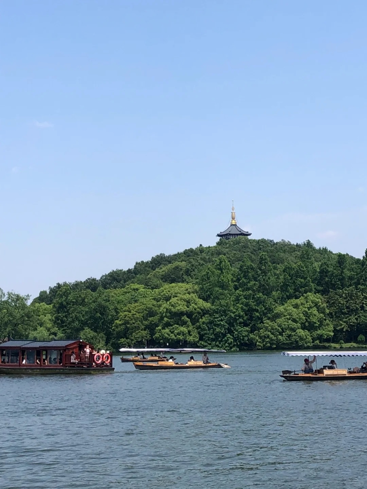 西湖遊船的愜意畫面。湖面波光粼粼，幾艘遊船悠然漂盪