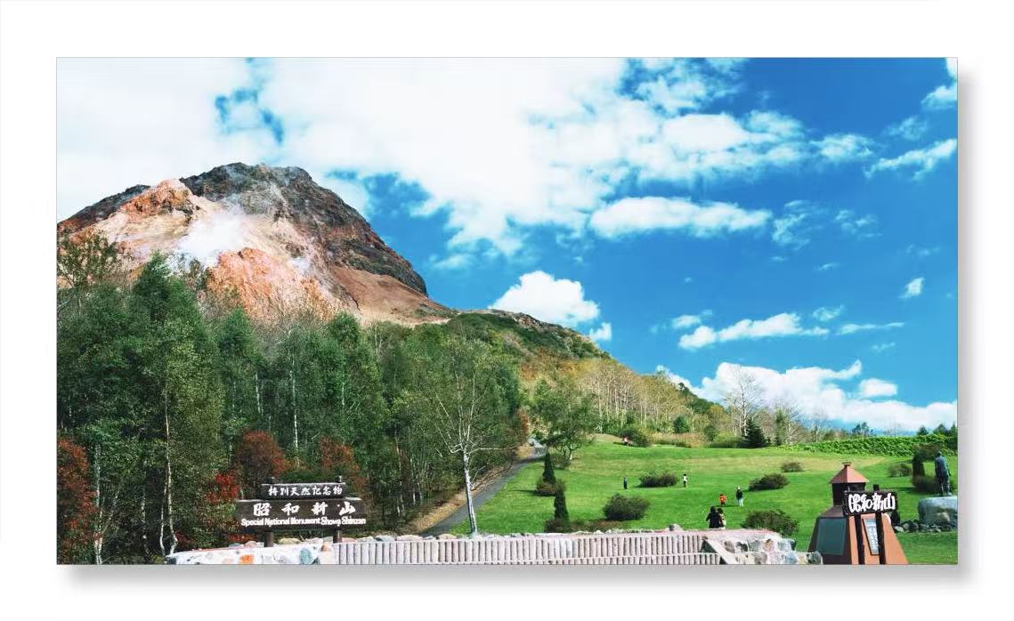 在昭和新山，可見在青空和藍色湖水的襯托下，構成強烈對比、裊裊冒煙的紅色火山