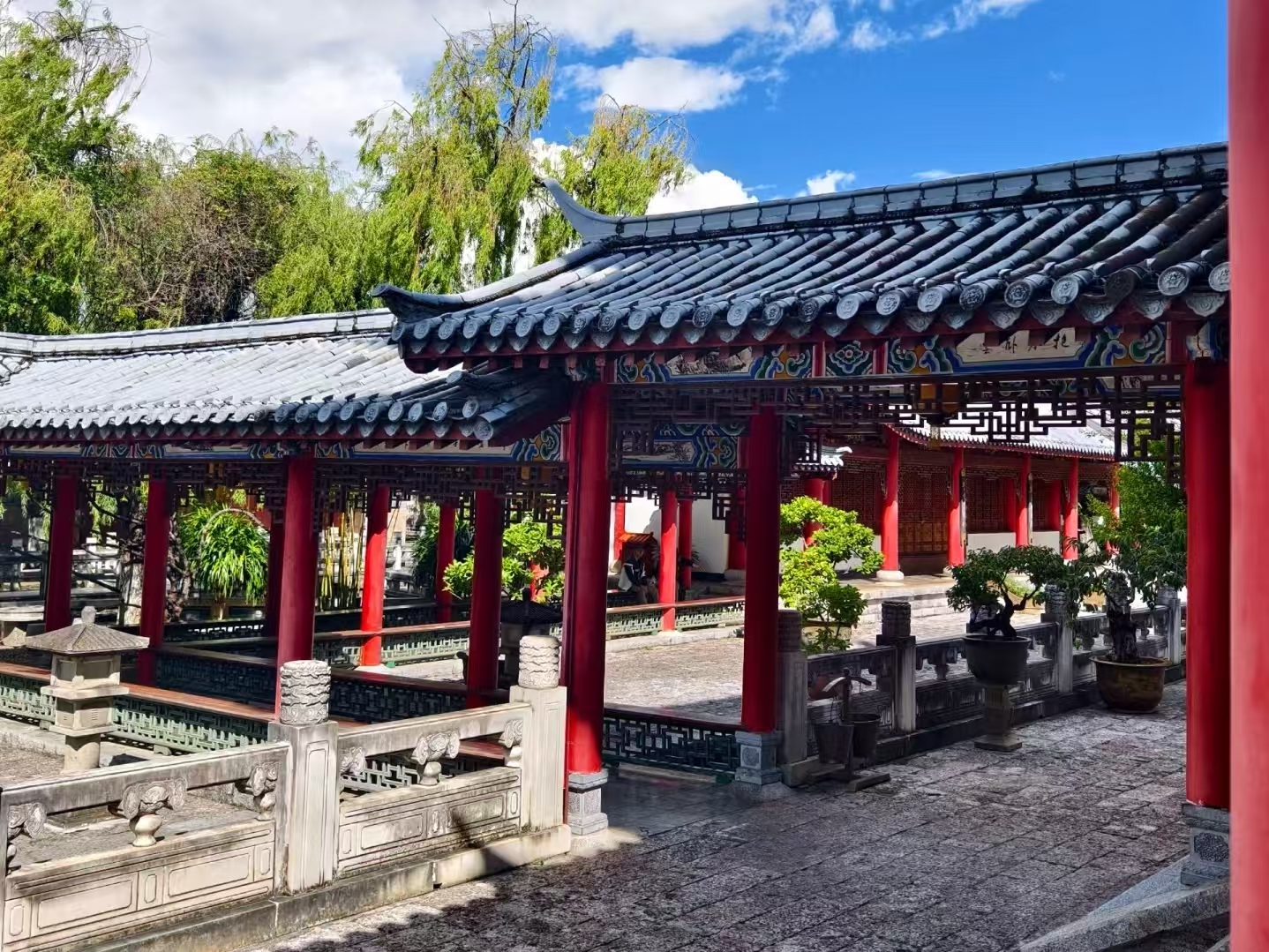 木府庭院迴廊近景，青瓦廊頂的彩繪清晰細膩，硃紅立柱錯落有致