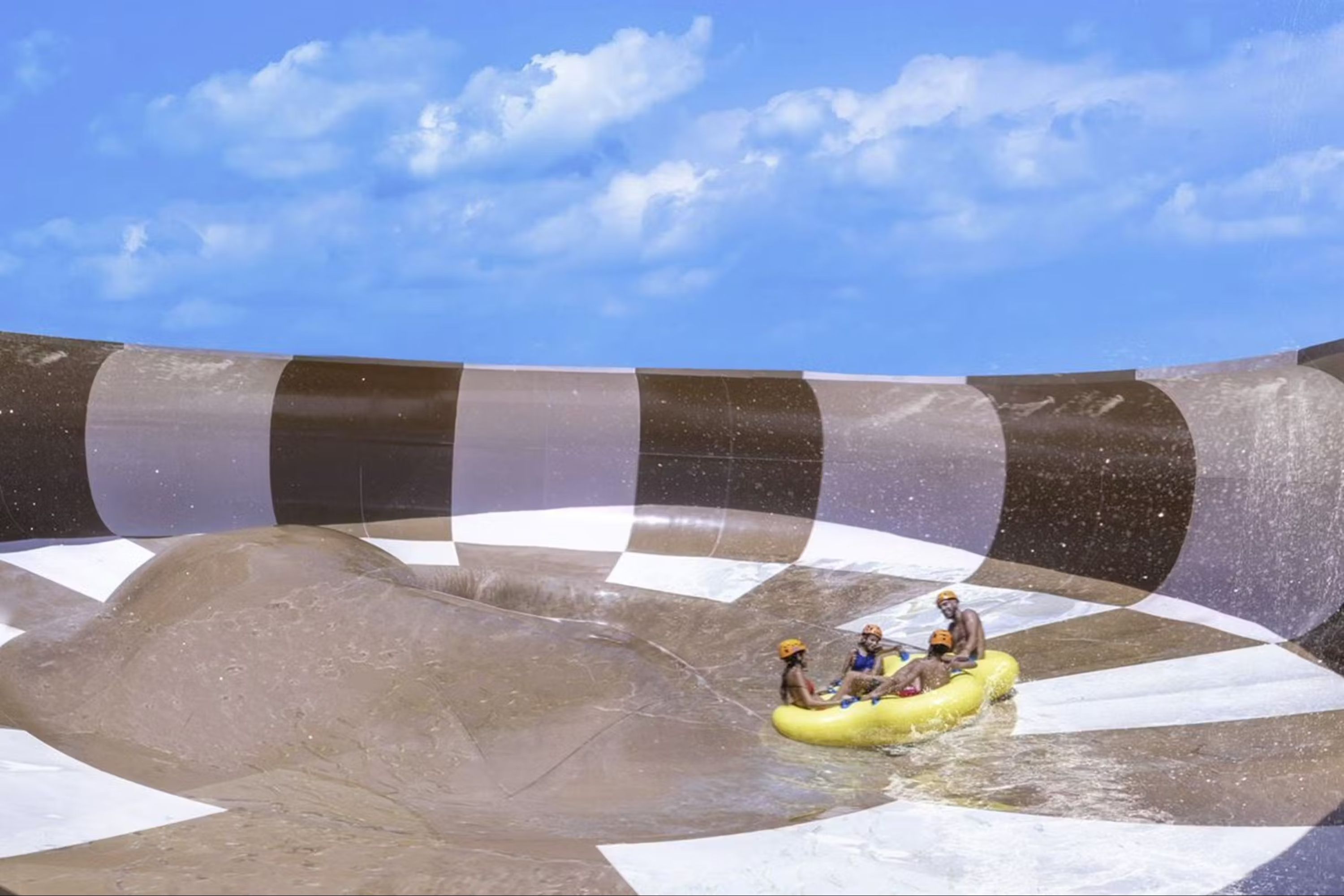 Friends laugh and splash as they raft down a winding Xplor water slide