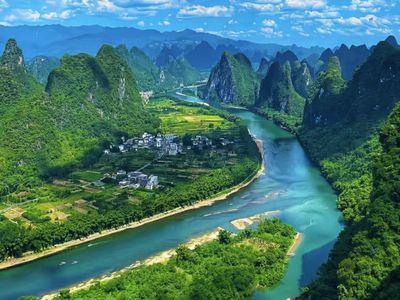灕江蜿蜒穿行於峰林之間，青黛山巒與碧綠田疇相映，村落點綴其間，宛如大地潑墨畫卷