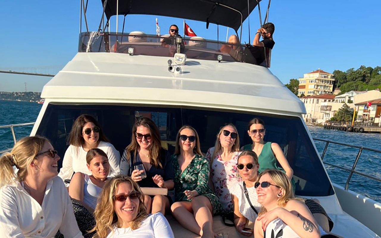 Friends relax with drinks onboard while the yacht drifts beside a peaceful island