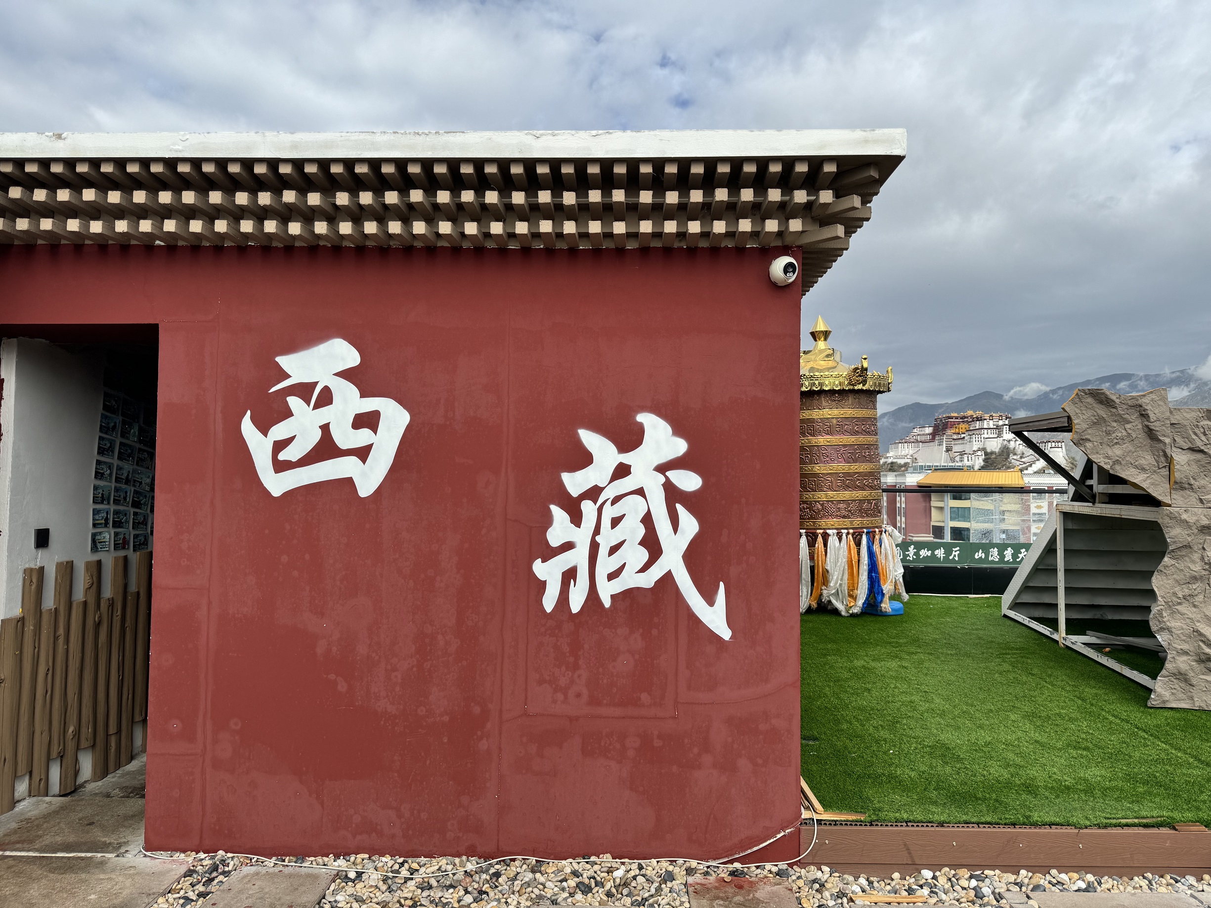 紅牆寫有西藏二字，一旁轉經筒正對布達拉宮