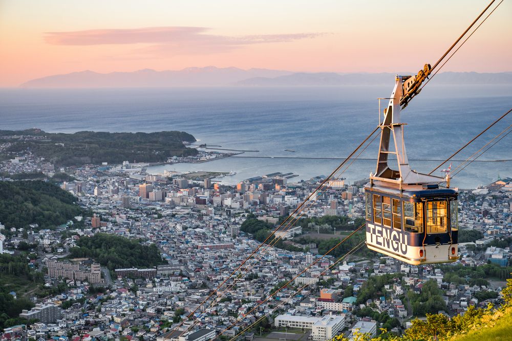 這座海拔532.3公尺的山峰因形似日本神話中天狗的長鼻而得名，卻以360度全景山海畫卷征服無數旅人。這裡不僅是電影《情書》中茫茫雪原的取景地，更是一座懸浮於天空的幻想庭園。當纜車穿越雲層的那一刻，便能明白為何日本人說「天狗山是離天國最近的觀景台」。
※ 天狗山纜車費用敬請自理。

天狗山纜車官網公告：2025年11月1日至11月30日期間進行維修，暫停運行。

於上述期間或遇強風、大雪導致纜車臨時停駛時，天狗山約90分鐘的遊覽時間將改為增加小樽運河與白色戀人公園參觀。