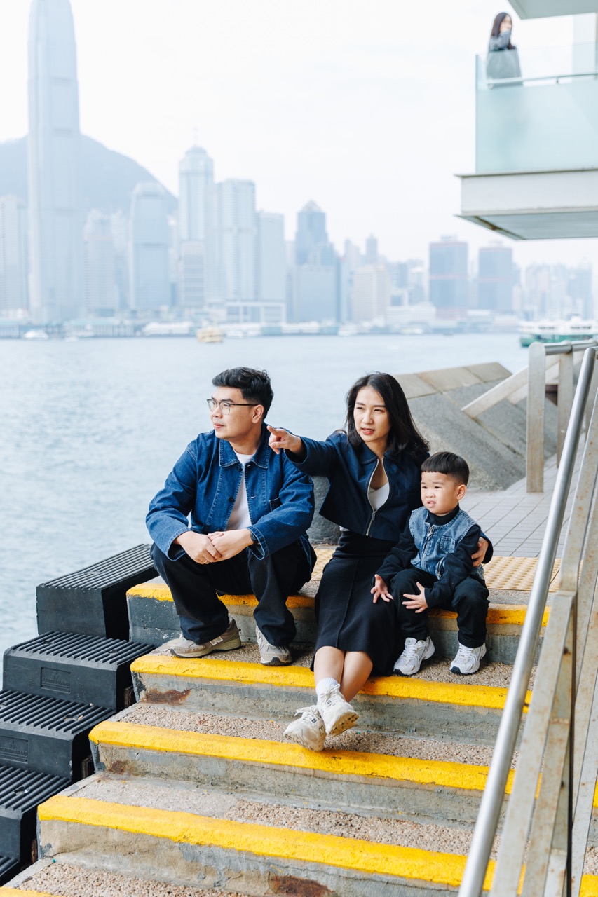 A candid moment of togetherness framed by the breathtaking skyline and vibrant lights of Hong Kong’s bustling harbor.