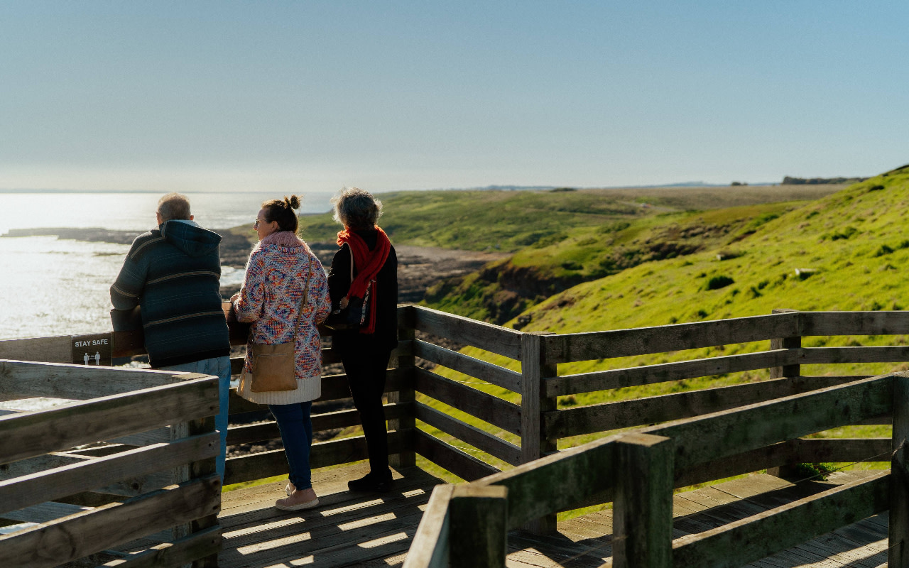 遊客們漫步於海風輕拂的木棧道上,俯瞰壯麗的懸崖峭壁與拍打海岸的洶湧海浪。 遊客們漫步於海風輕拂的木棧道上,俯瞰壯麗的懸崖峭壁與拍打海岸的洶湧海浪。