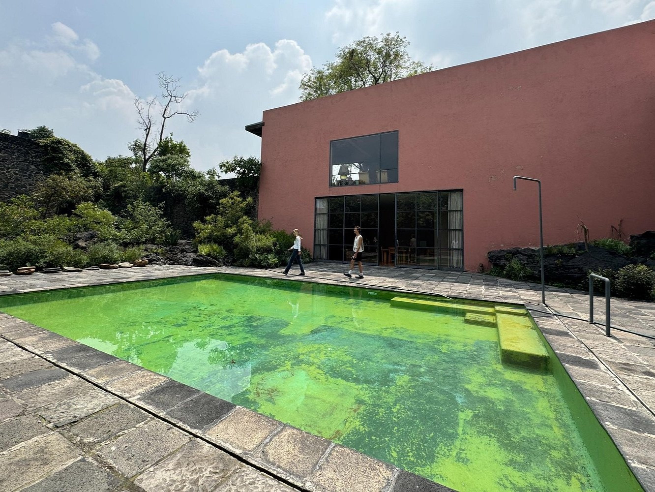 Pastel pink walls glow softly against the rugged volcanic rock courtyard backdrop