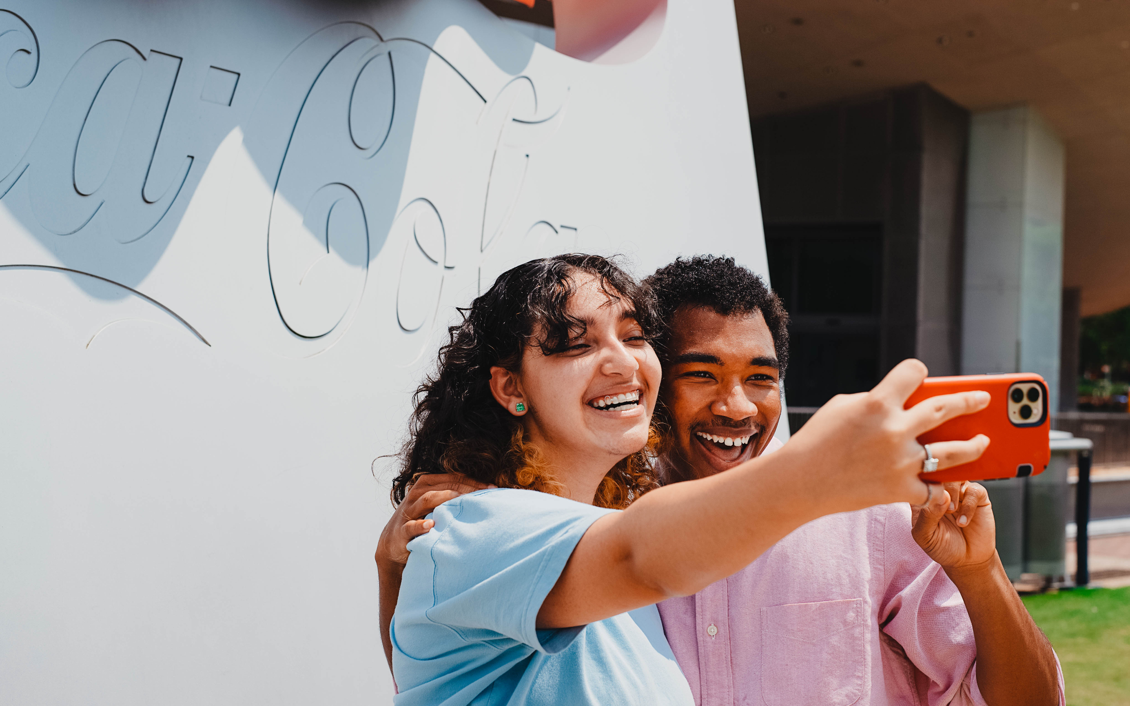 在標誌性的可口可樂標誌前自豪地拍一張有趣的自拍照