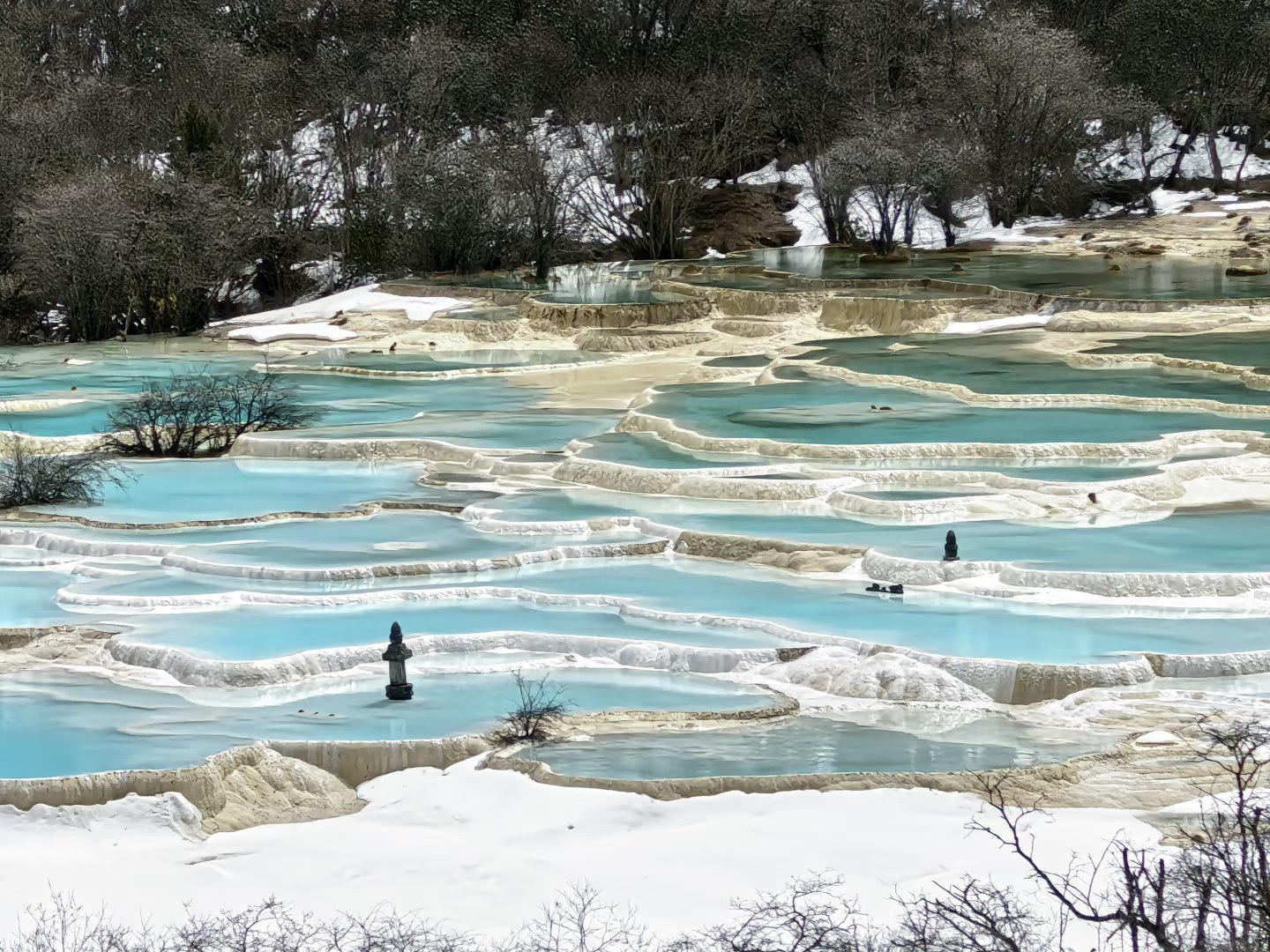 冰雪未消的黃龍彩池裡，幾座小塔靜靜佇立，白藍相間的景色帶著未褪的清冽，雪水與鈣華池交織，藏著高原獨有的靜謐詩意與冬日限定的仙氣