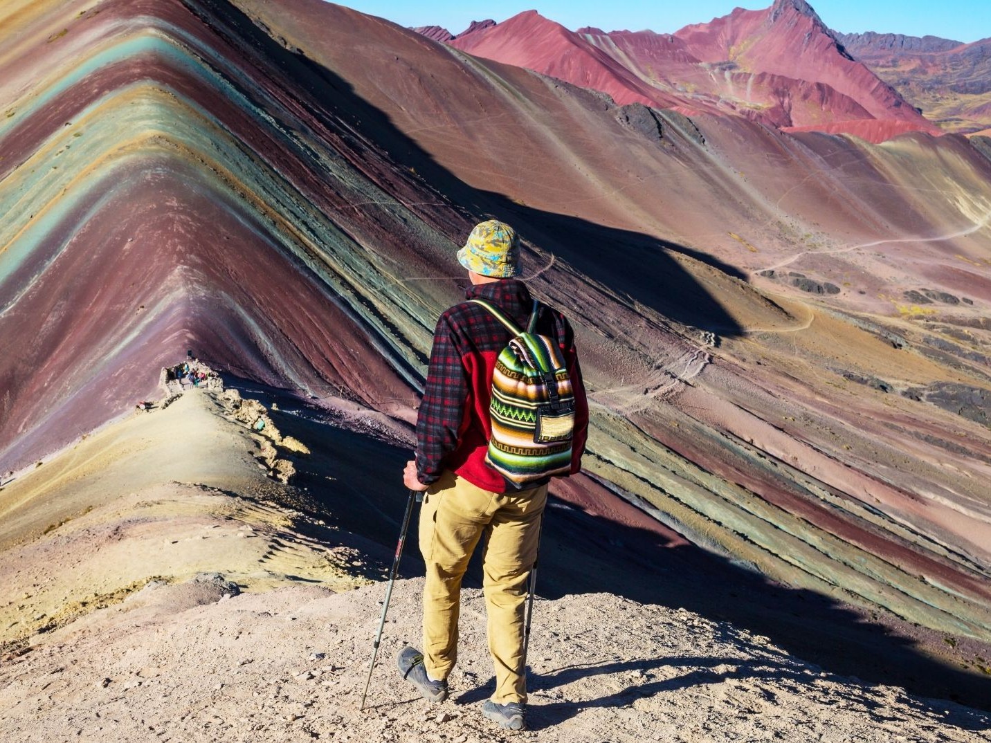 A happy traveler poses proudly at the scenic Rainbow Mountain viewpoint, surrounded by colorful landscapes