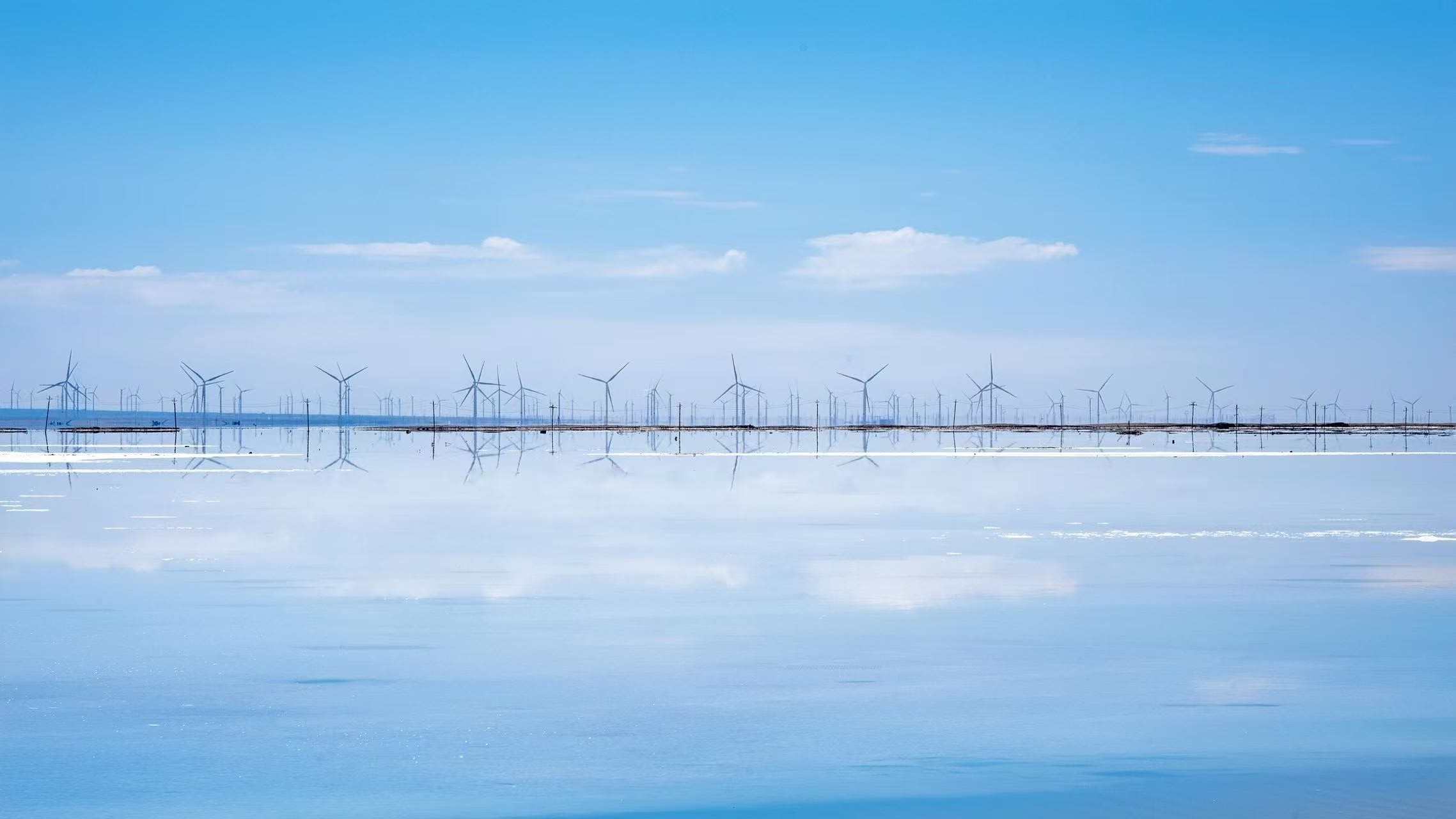 澄澈平靜的鹽湖水面宛如鏡面,遠方成片風力發電機整齊排布,風輪的倒影完整復刻在湖面之上,淡藍晴空飄著細碎雲朵,畫面清透治癒,氛圍感靜謐舒緩 澄澈平靜的鹽湖水面宛如鏡面,遠方成片風力發電機整齊排布,風輪的倒影完整復刻在湖面之上,淡藍晴空飄著細碎雲朵,畫面清透治癒,氛圍感靜謐舒緩