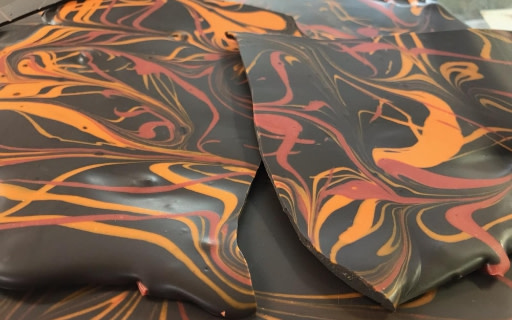 盡享黑巧克力脆片的藝術漩渦，點綴鮮豔的橘色與紅色。