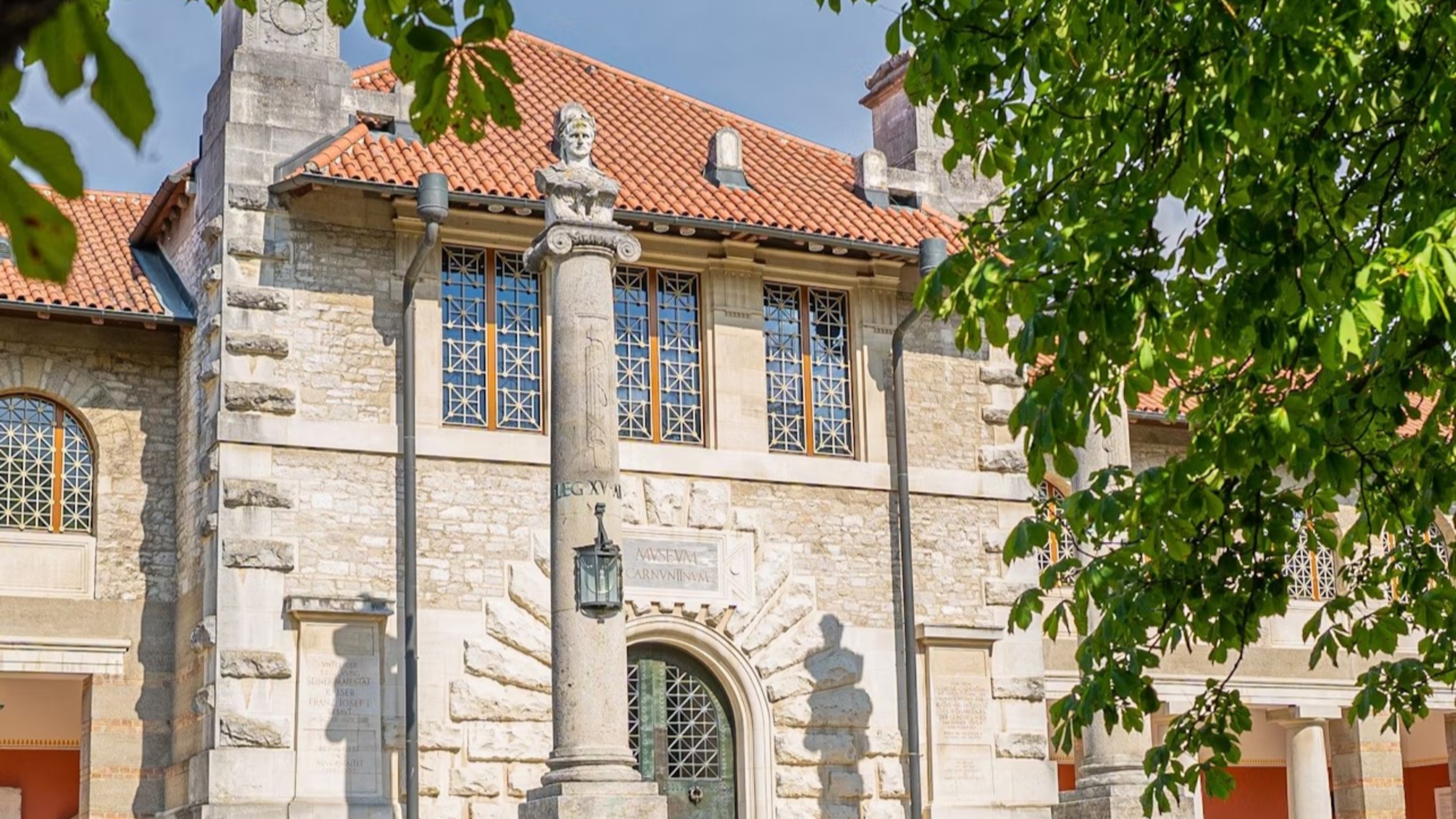 Step into history: a beautiful stone building with an ancient column and lush greenery
