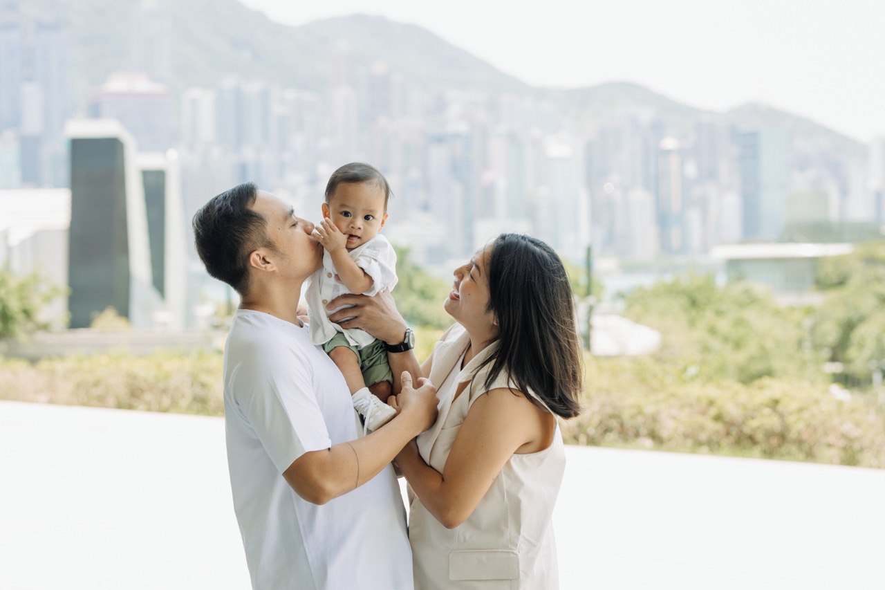 A sweet family moment, with the breathtaking view of Victoria Harbour in the background.