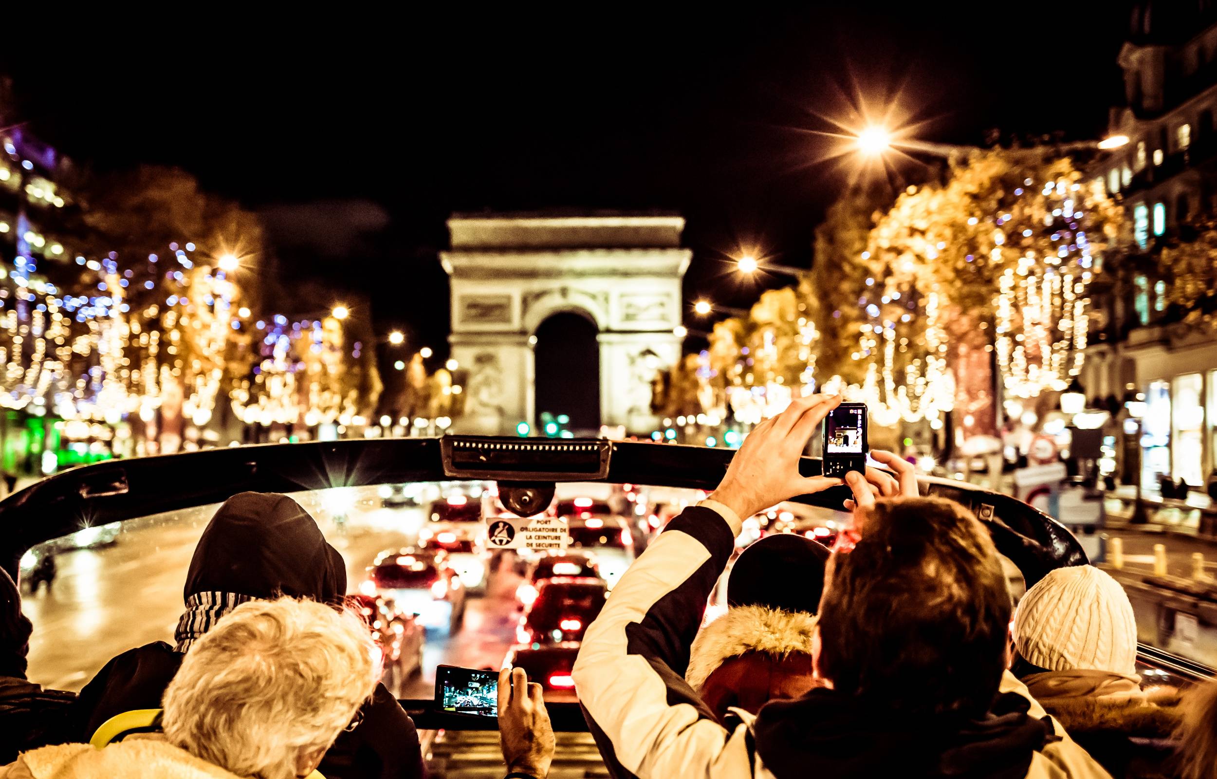 在聖誕節之旅中,遊客搭乘敞篷巴士,捕捉燈火通明的凱旋門 在聖誕節之旅中,遊客搭乘敞篷巴士,捕捉燈火通明的凱旋門
