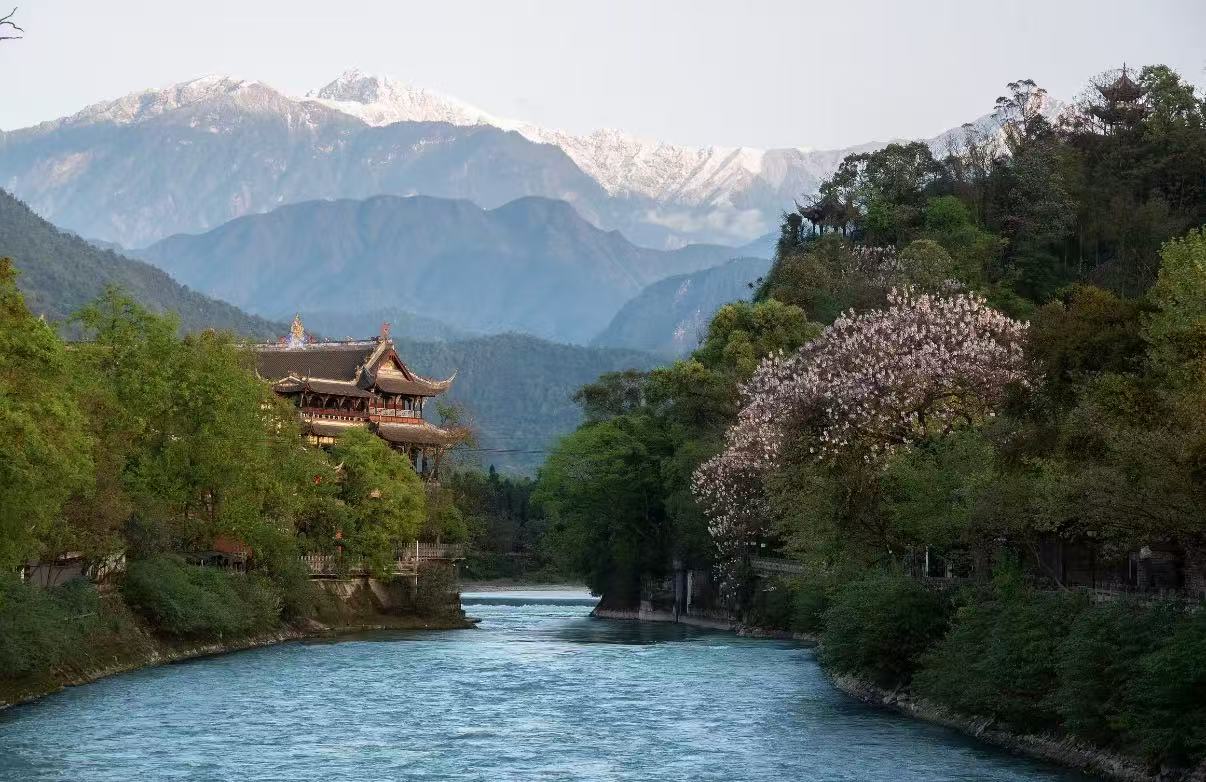 都江堰的河道風光如畫,江水澄澈如藍,岸邊古建飛簷隱於綠樹間,粉花滿枝盛放,遠處雪山巍峨,勾勒出山水古堰的靜謐詩意 都江堰的河道風光如畫,江水澄澈如藍,岸邊古建飛簷隱於綠樹間,粉花滿枝盛放,遠處雪山巍峨,勾勒出山水古堰的靜謐詩意